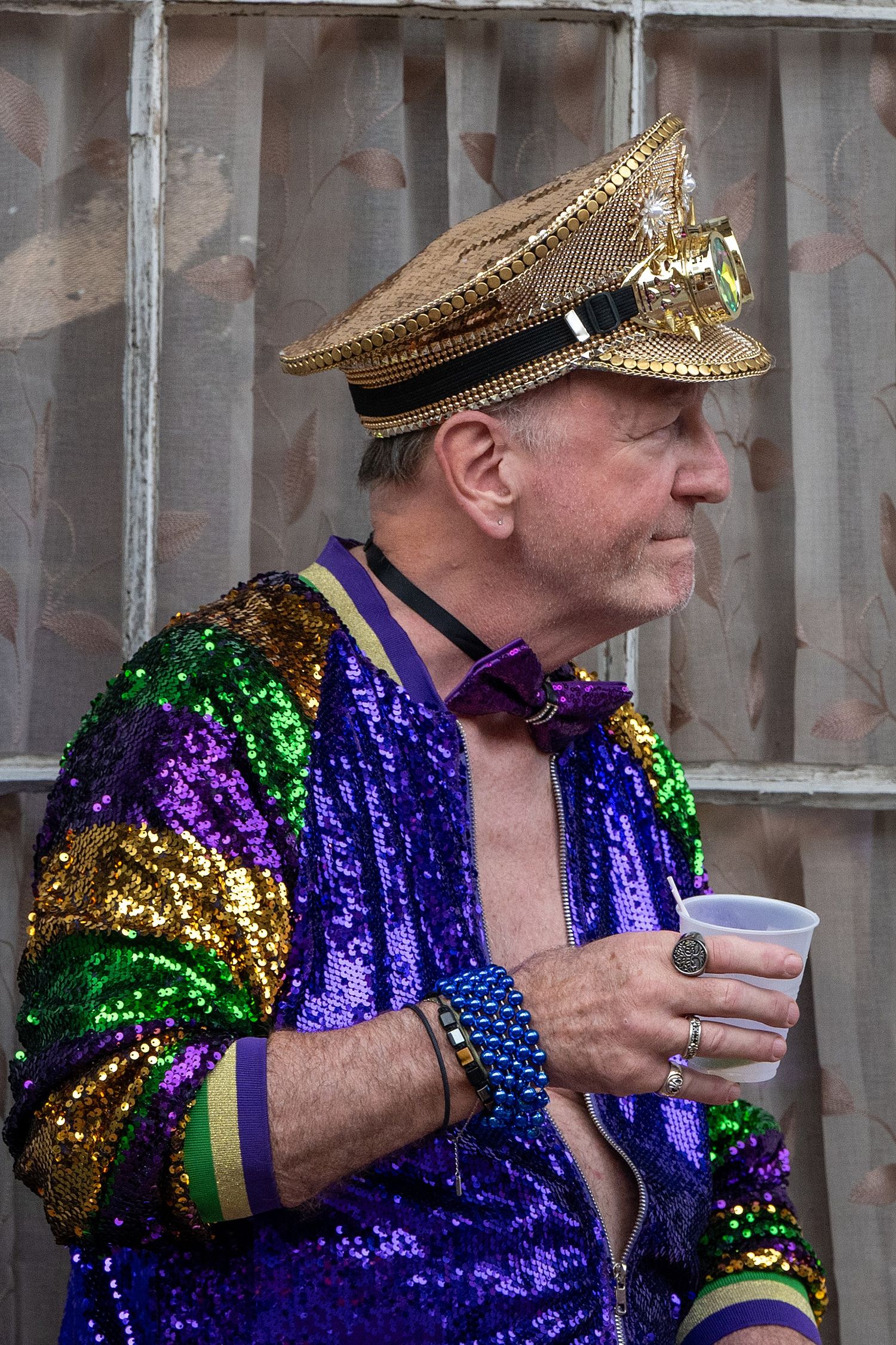 People in gold military-style hats and purple sequined outfits adorned with beads at a festival.