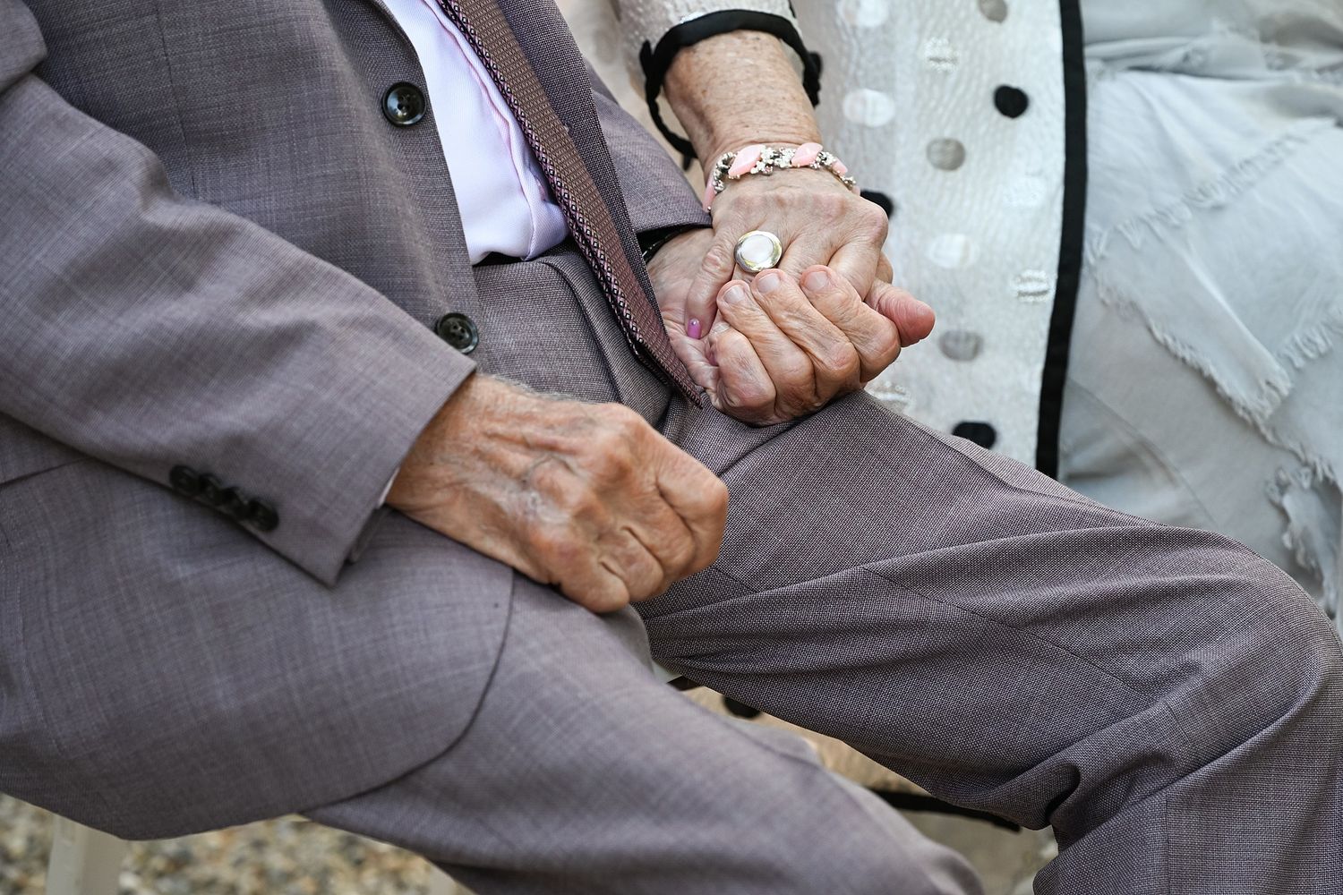 Close-up view of hands holding and examining a small electronic device or gadget in gray lighting.