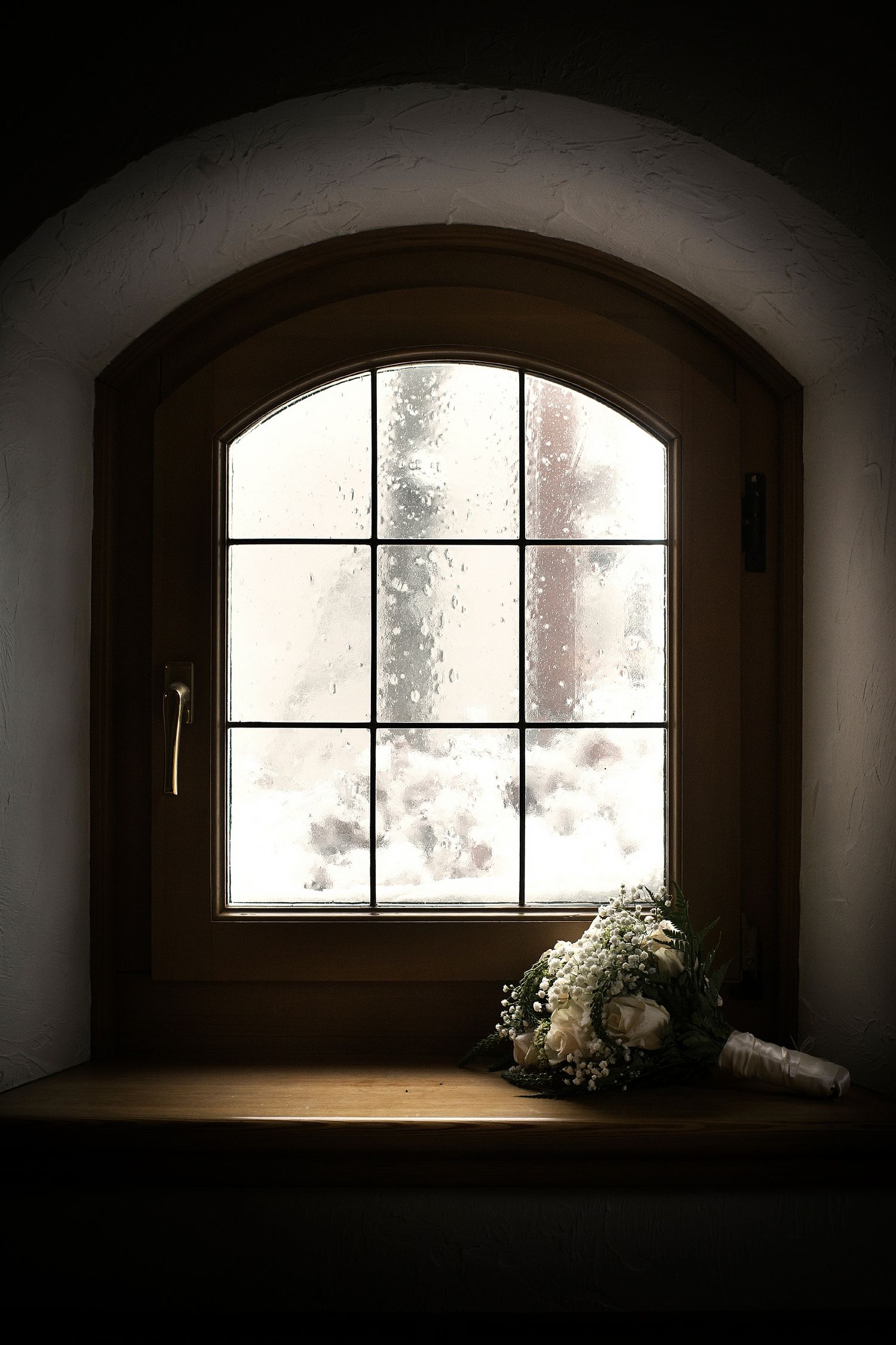 Arched windows with white flowers creating a moody, minimalist atmosphere.