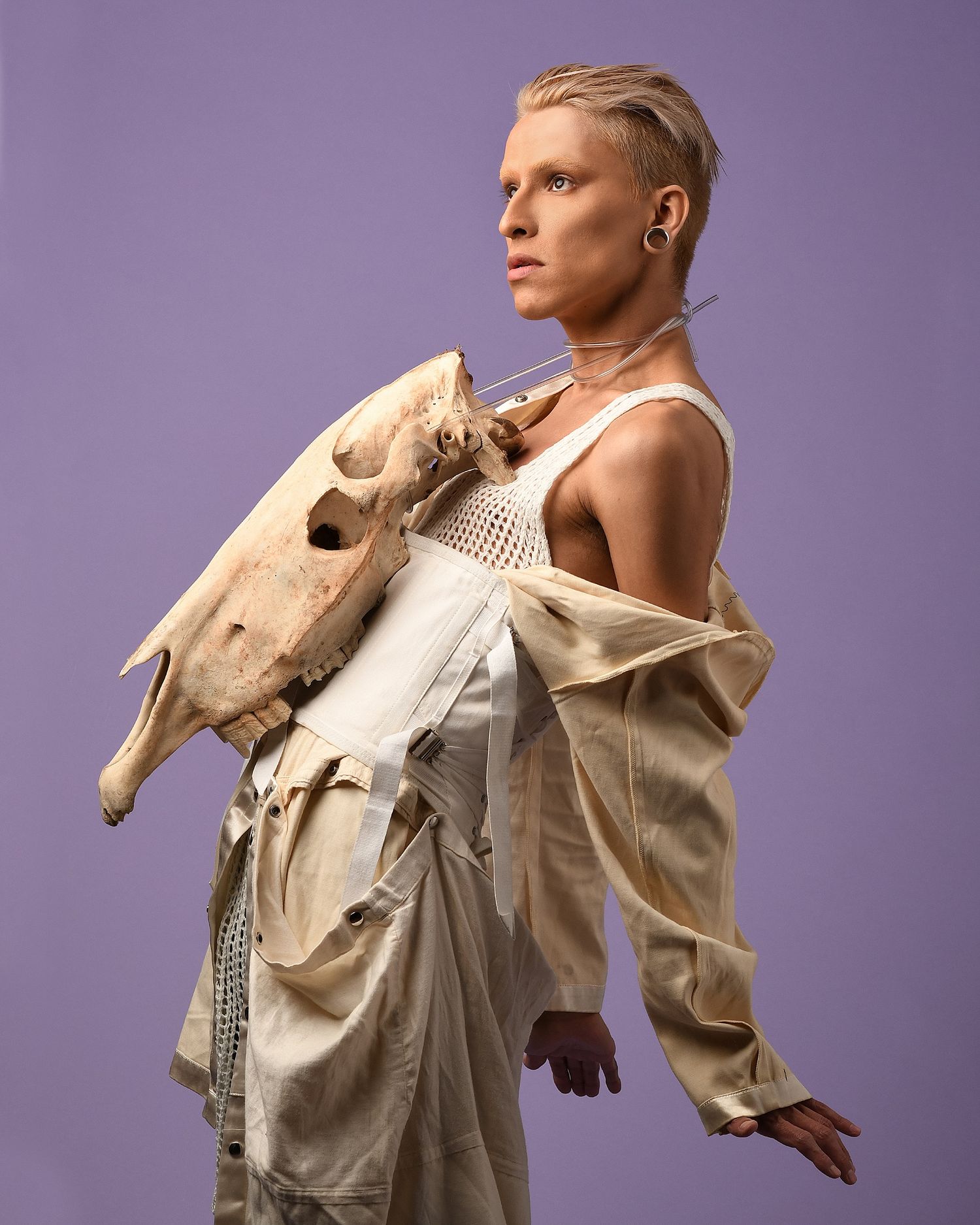 Fashion series showing movement in beige structured garment against purple backdrop.