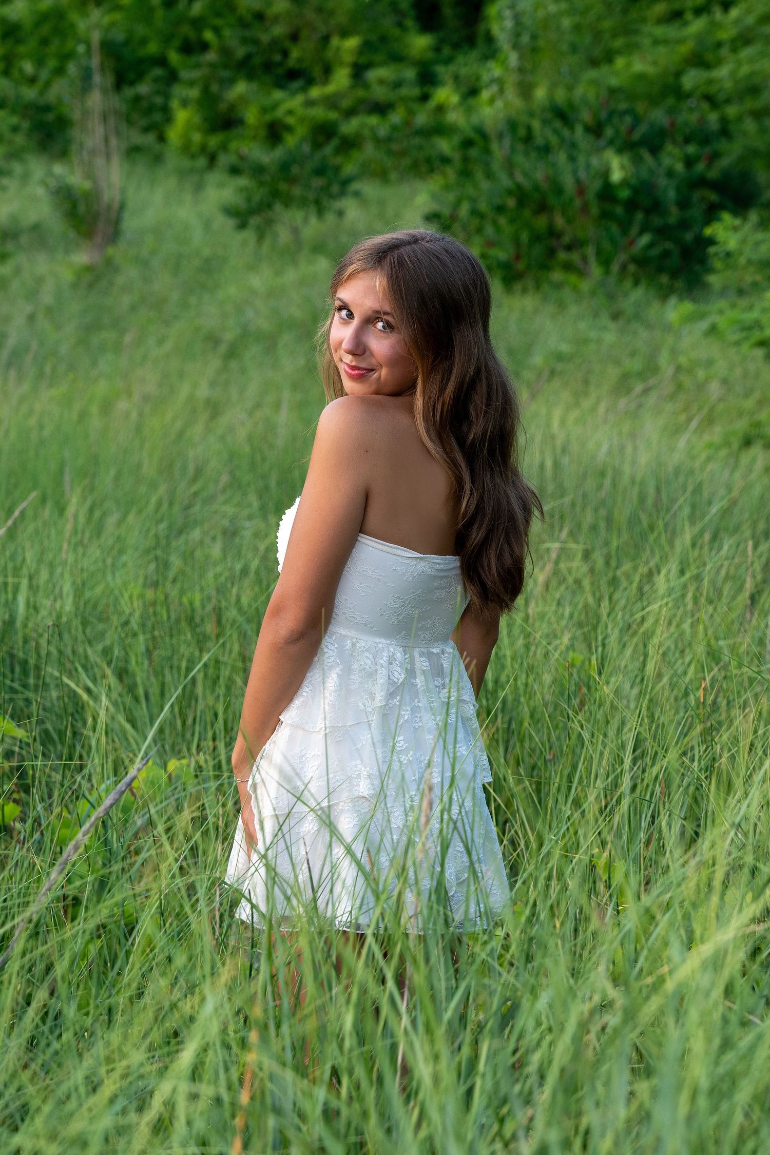 A white sundress photoshoot in tall green grass during golden hour.