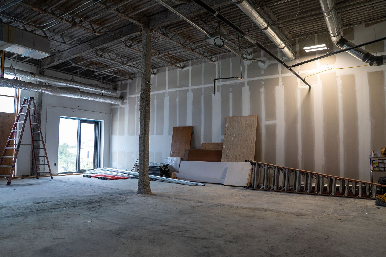 Open commercial space during construction phase showing support columns and unfinished walls.