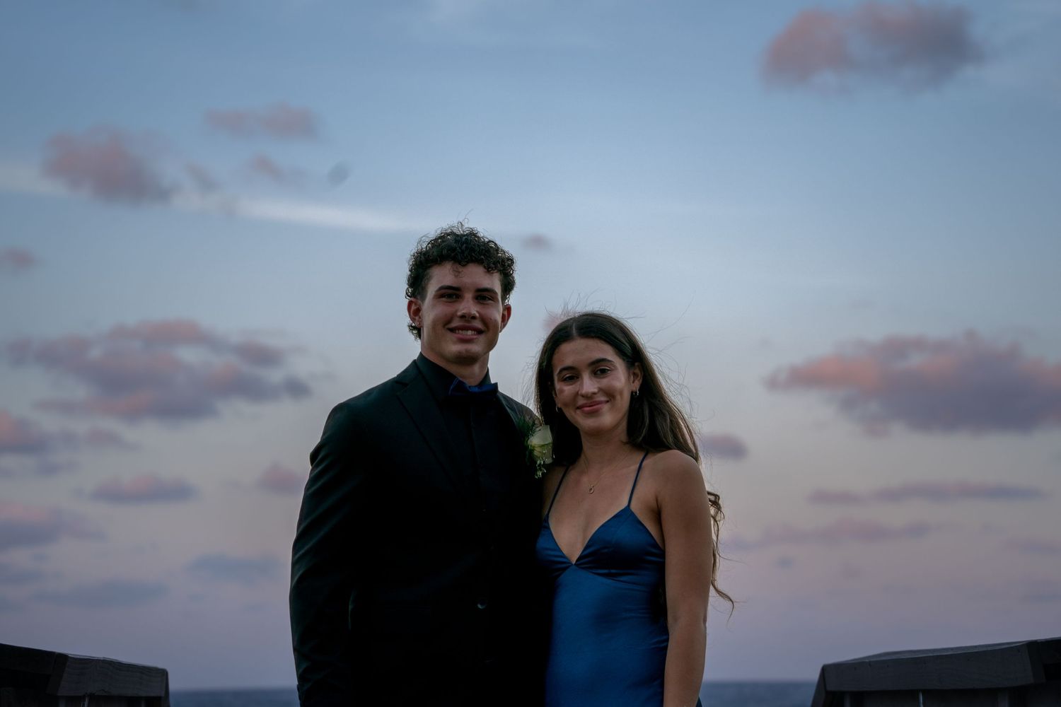 Sunset beach photoshoot with couple against cloudy sky.