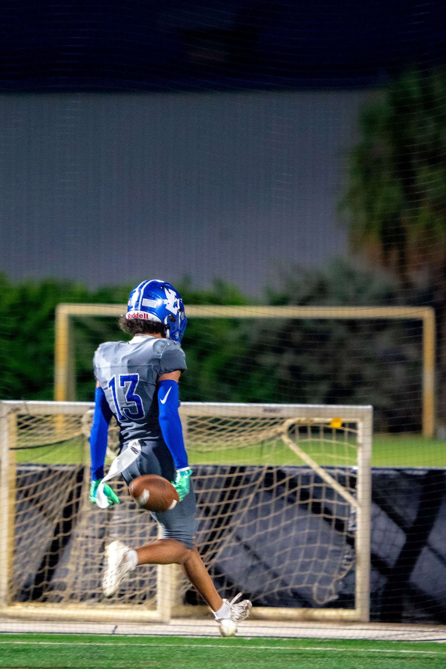 Football player dives dramatically in front of goal posts during an intense match.