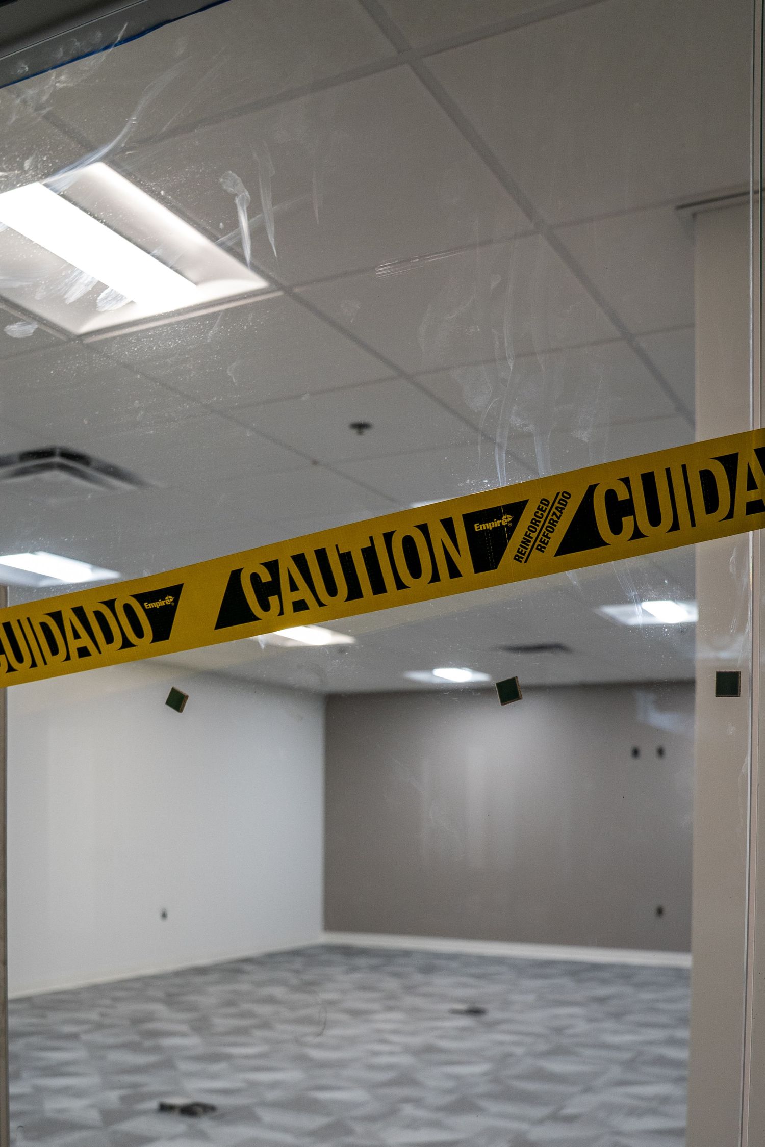 Empty commercial space under construction with caution tape visible and exposed ceiling fixtures.