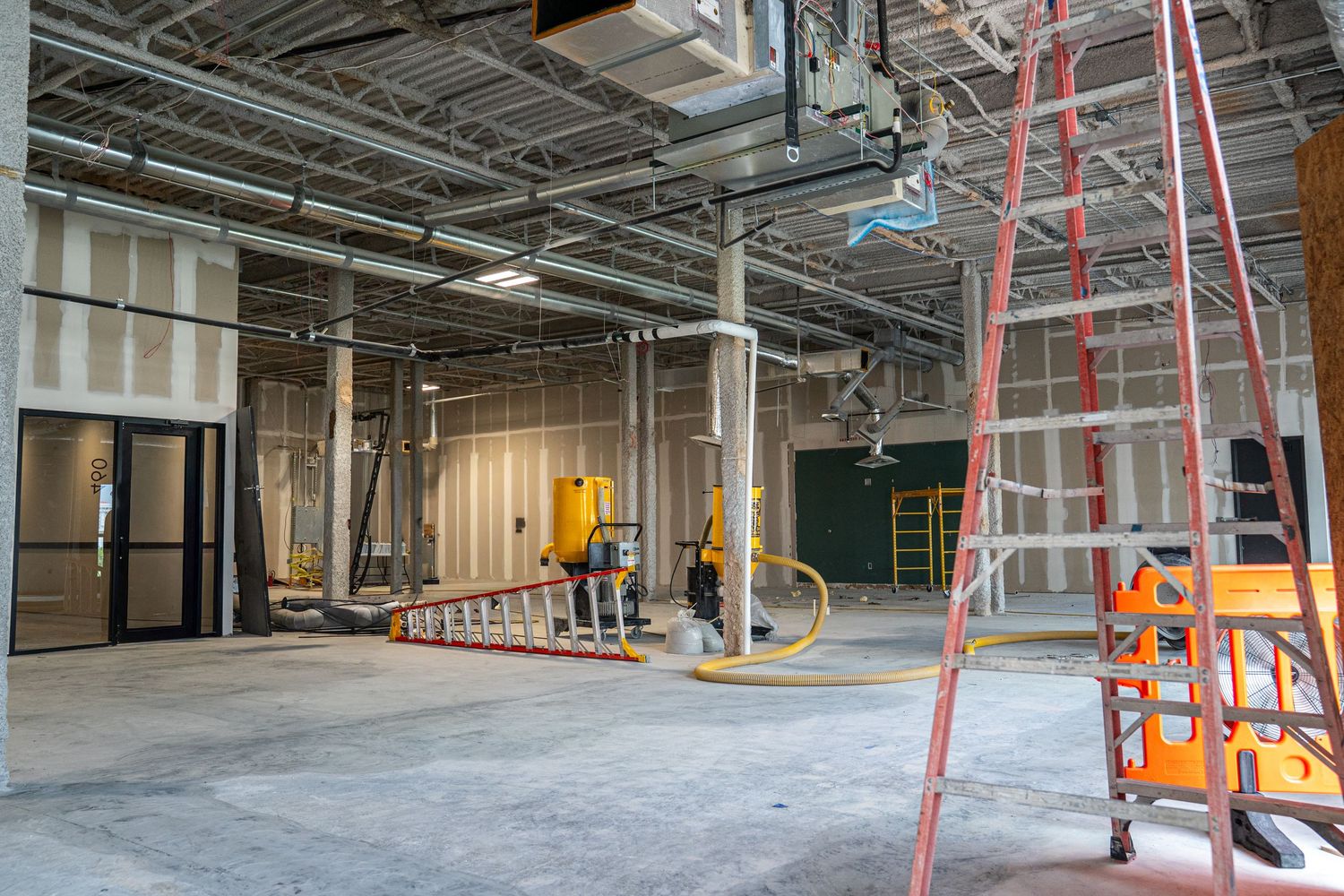 Commercial building interior during renovation with orange safety equipment and construction materials visible.