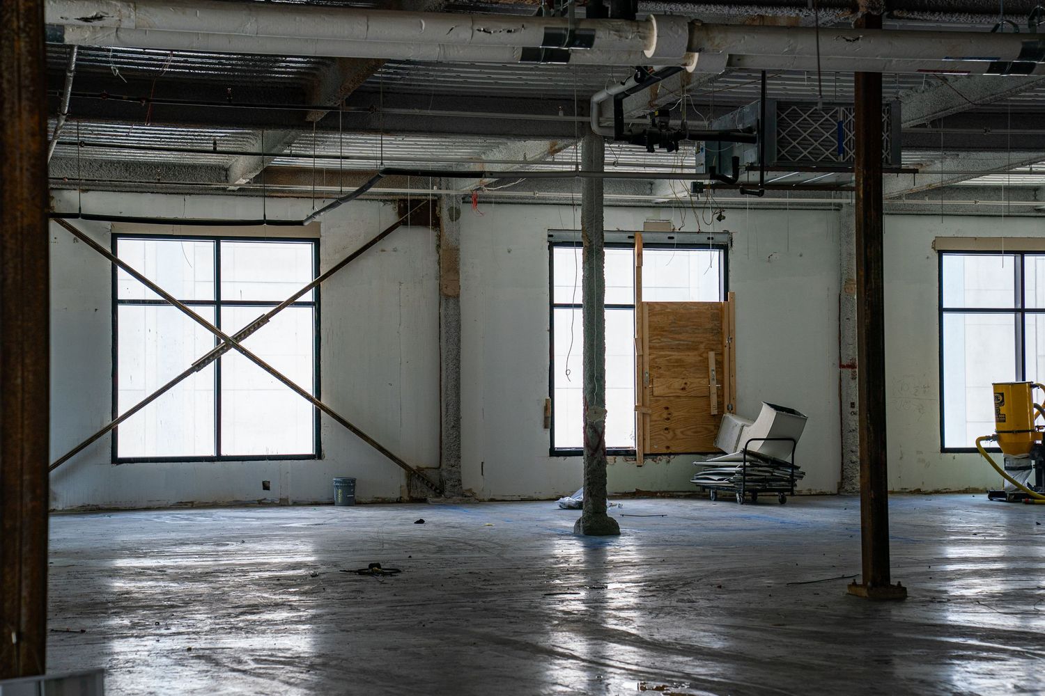 Wide angle view of vacant commercial space showing windows and support columns.
