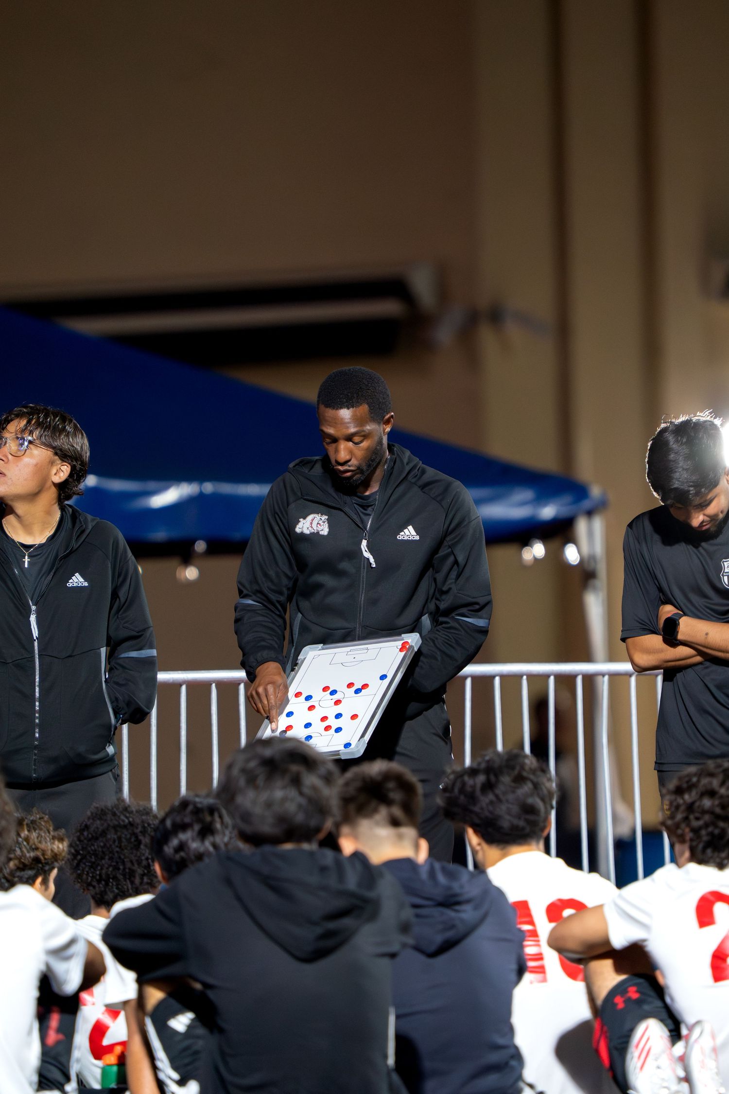 Team huddle in black jackets gathered around during sporting event.