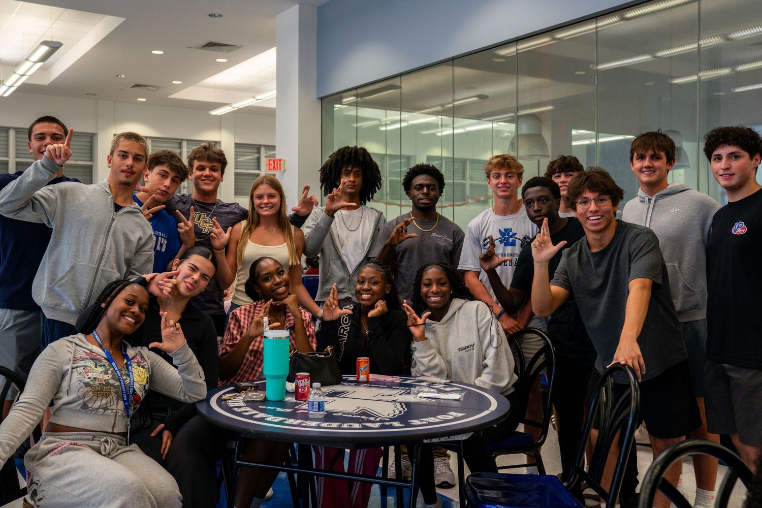 Students gathered around tables in a brightly lit indoor space.