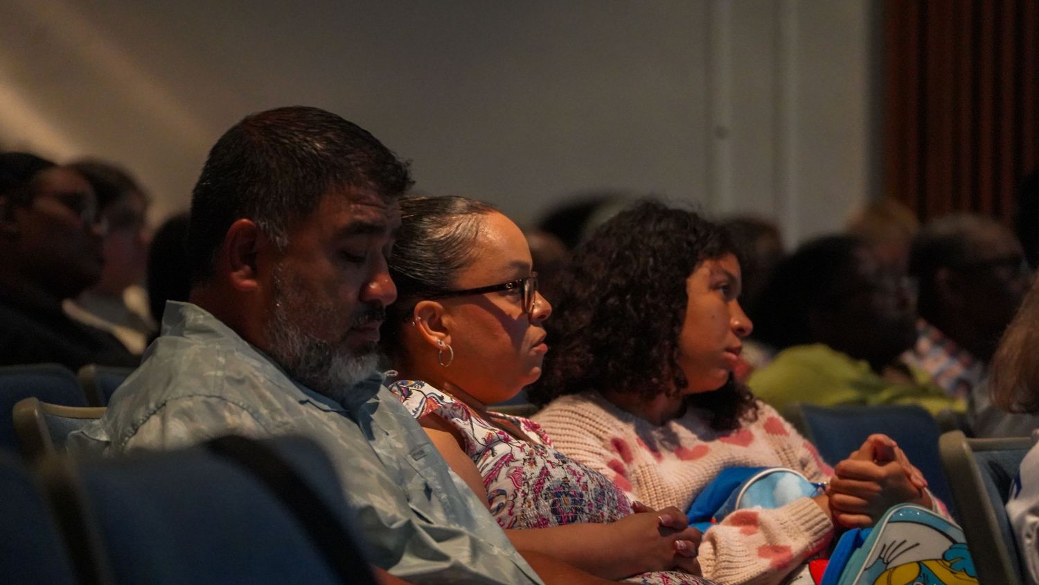 Audience members seated in theater chairs during a presentation.