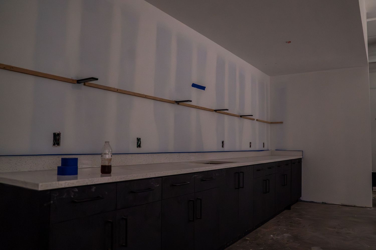 Newly constructed white walls with blue painter's tape markings in commercial space.