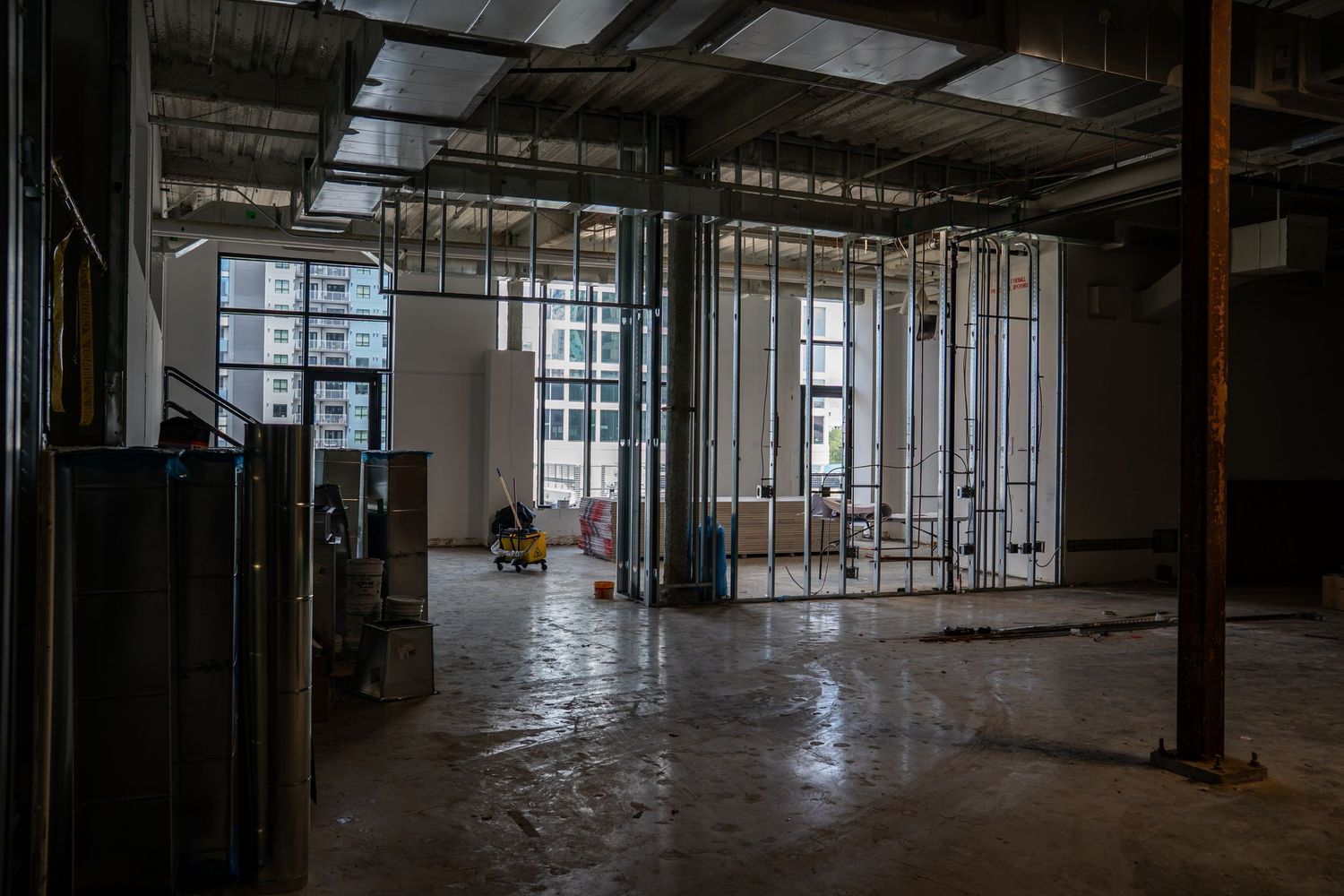 Panoramic view of a commercial building interior during renovation with exposed infrastructure.
