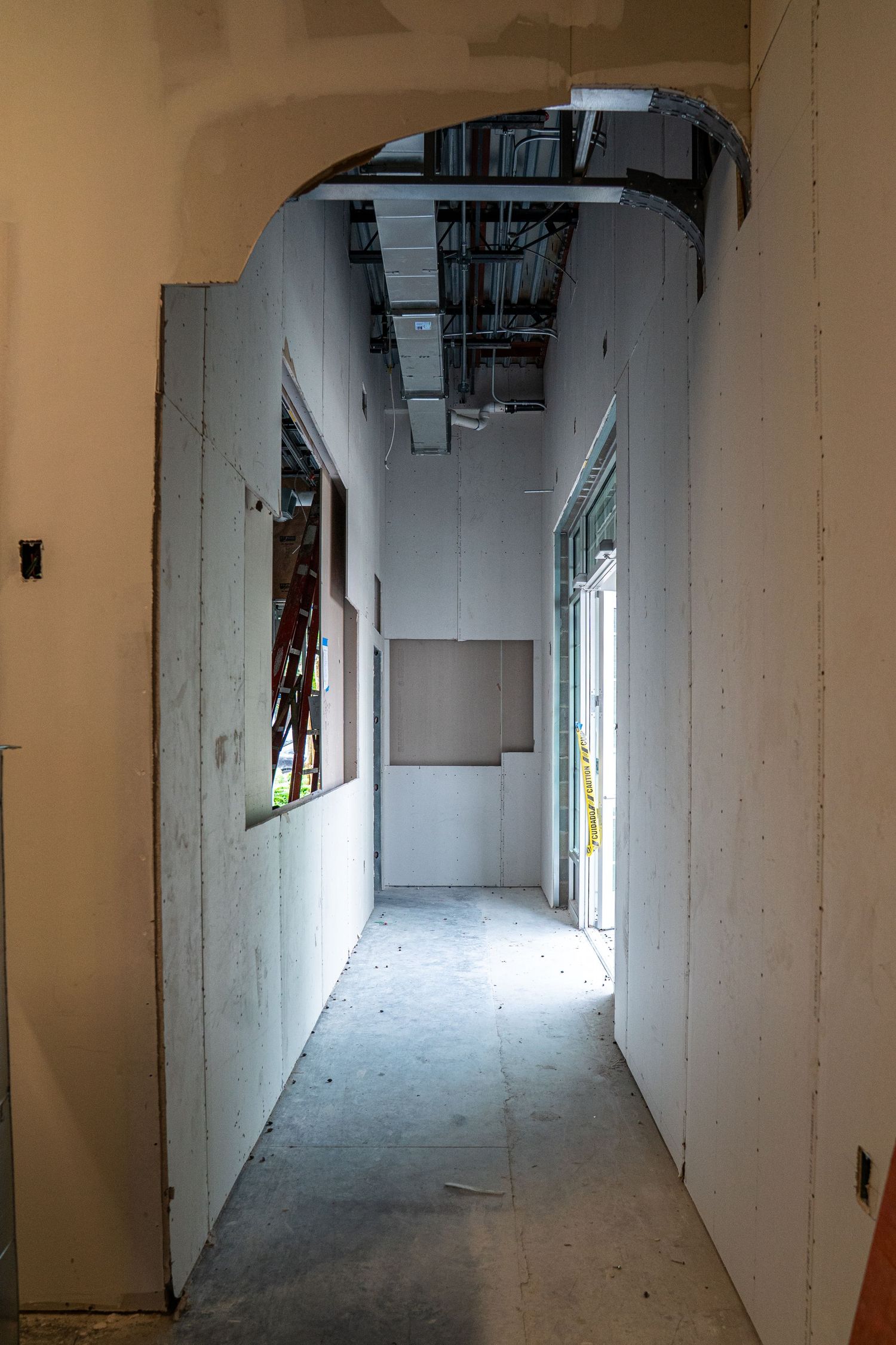 Long corridor with white walls and exposed concrete floor during construction phase.