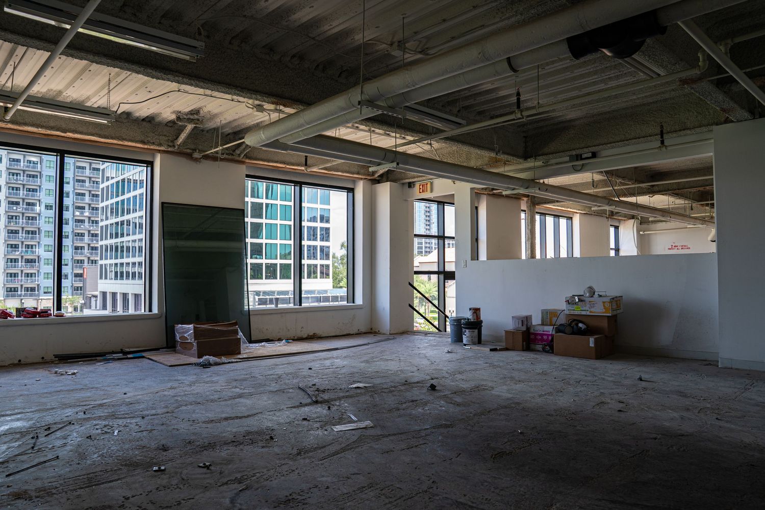 Panoramic view of vacant commercial space showing exposed ceiling systems and window walls.