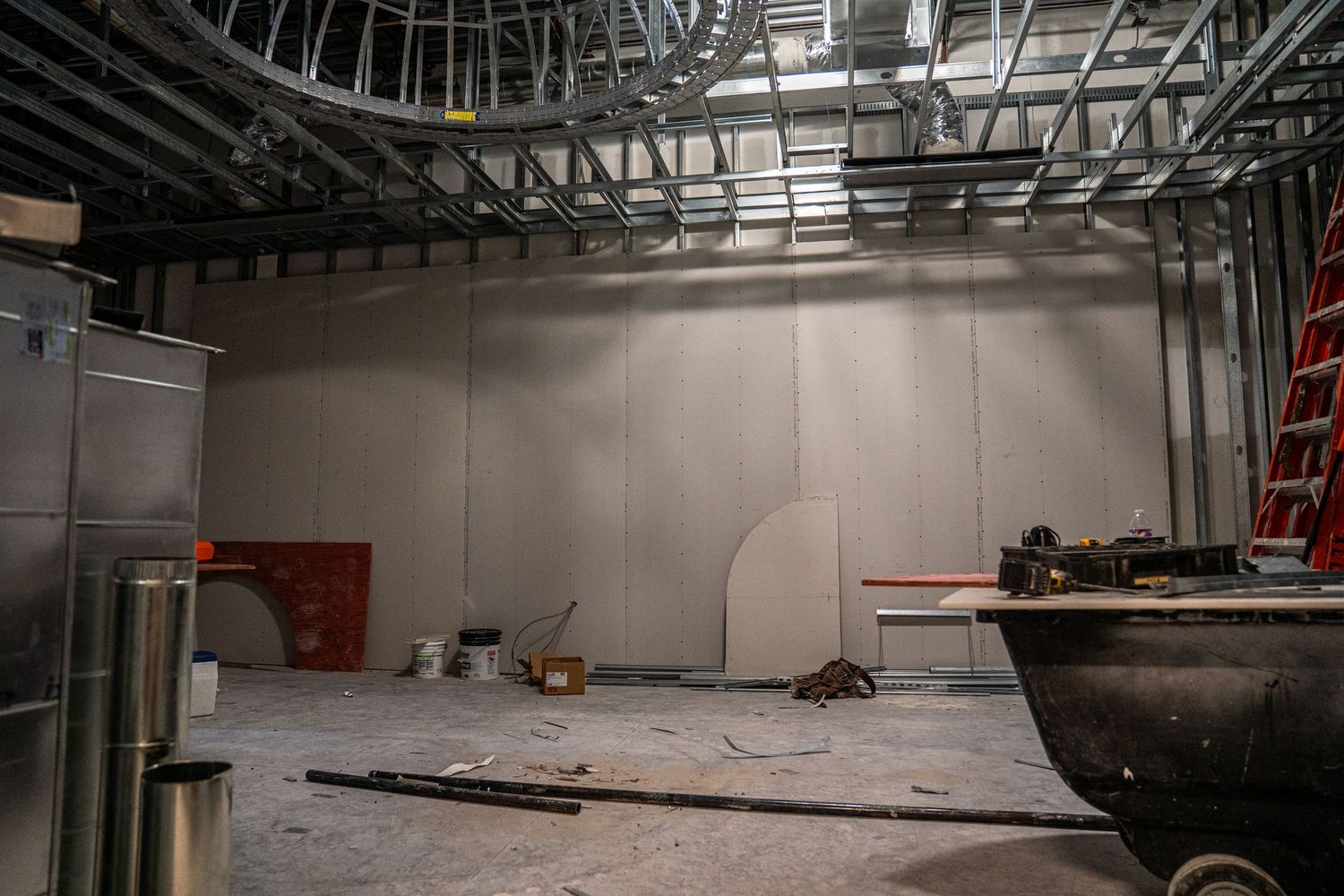 Long corridor under construction with metal framing and electrical conduit visible.