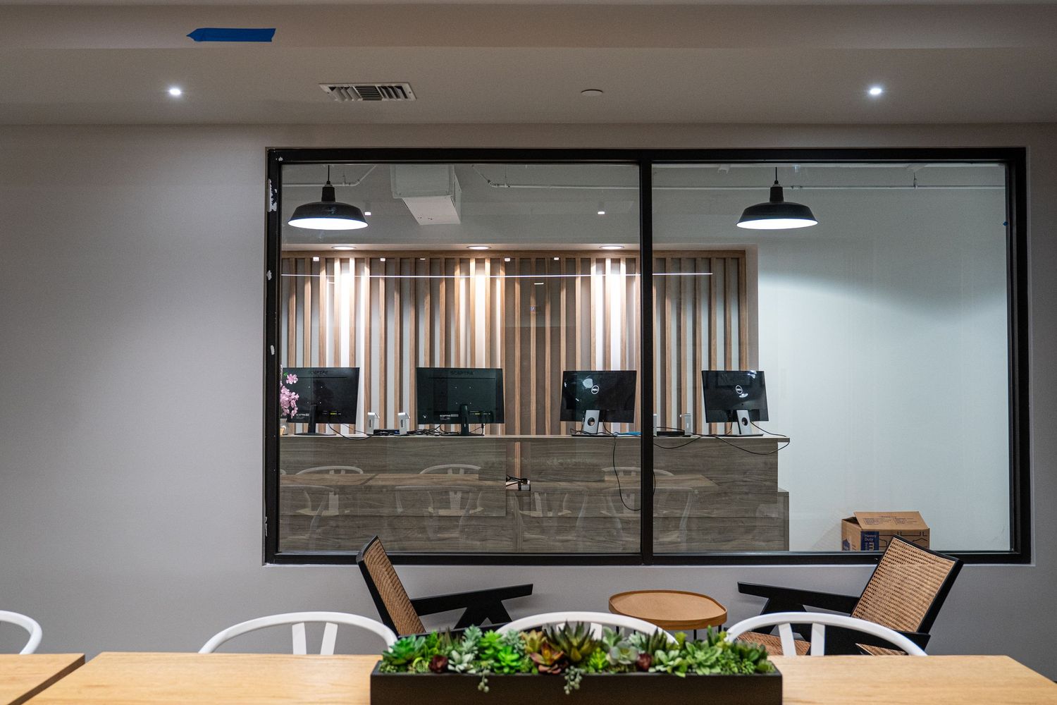 Open office interior with ergonomic furniture, glass partitions, and natural lighting from windows.