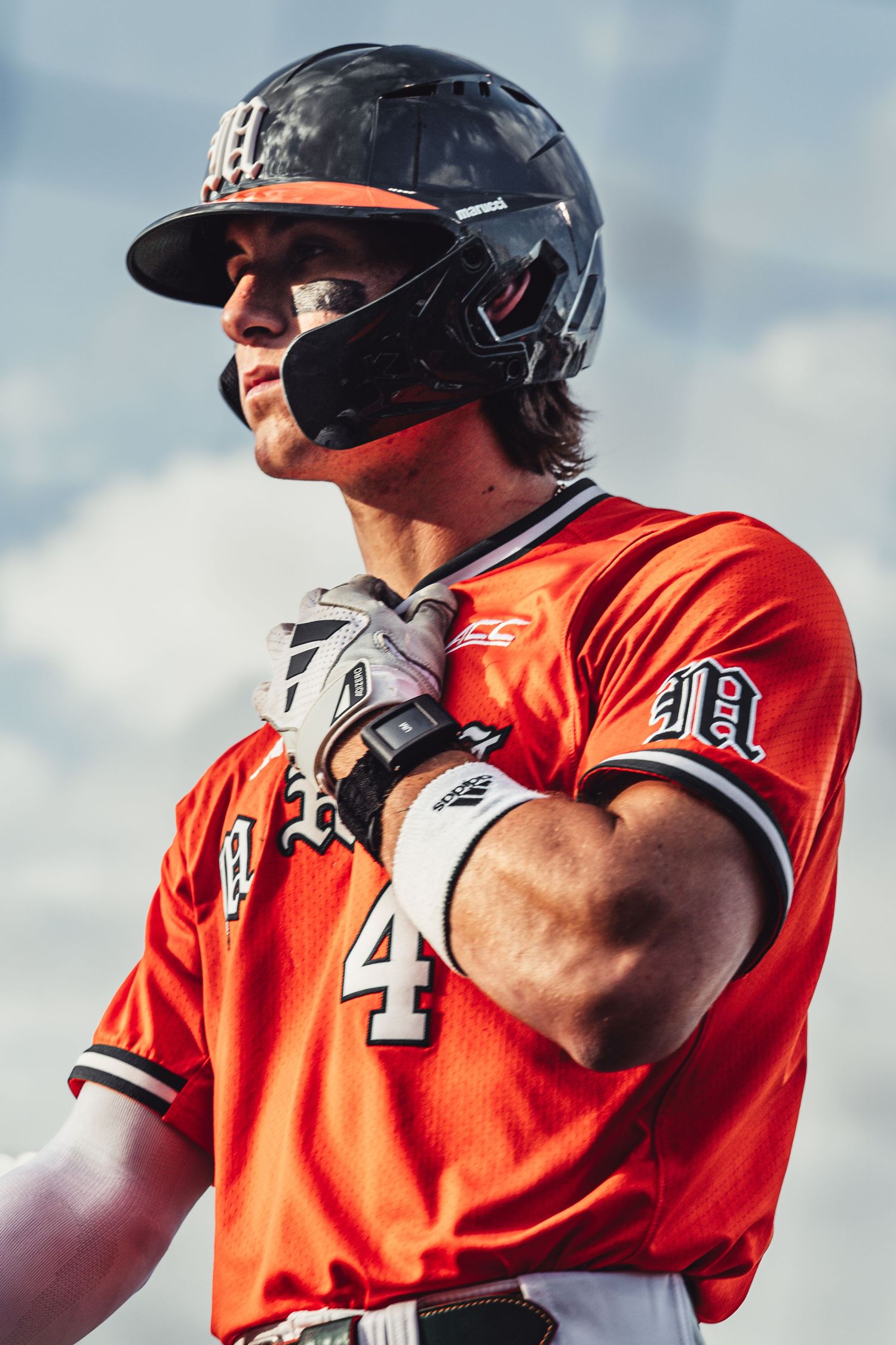 Baseball player in orange jersey number 4 wearing batting helmet and gloves, ready to bat during a game.