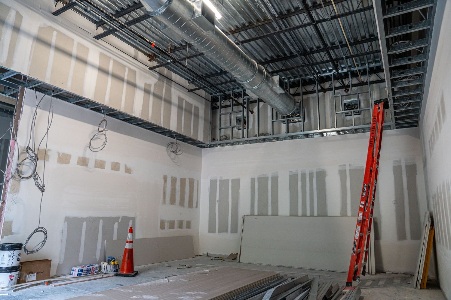 Empty retail space during construction phase showing mechanical systems and white walls.