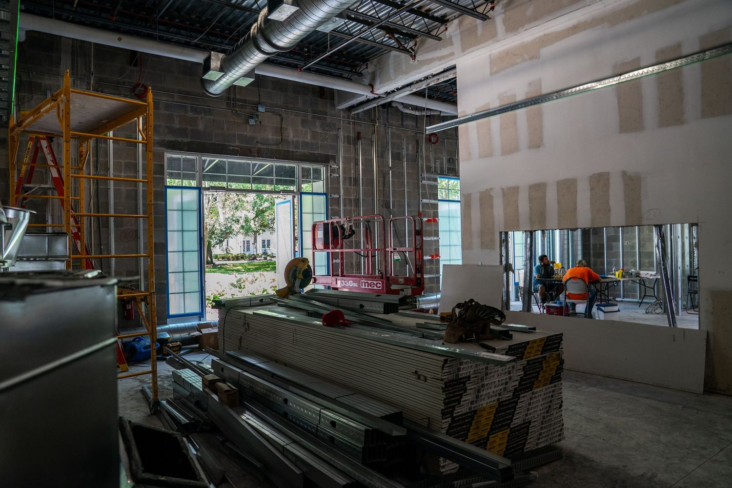Interior construction site showing metal framing and exposed ceiling with electrical and HVAC systems visible.