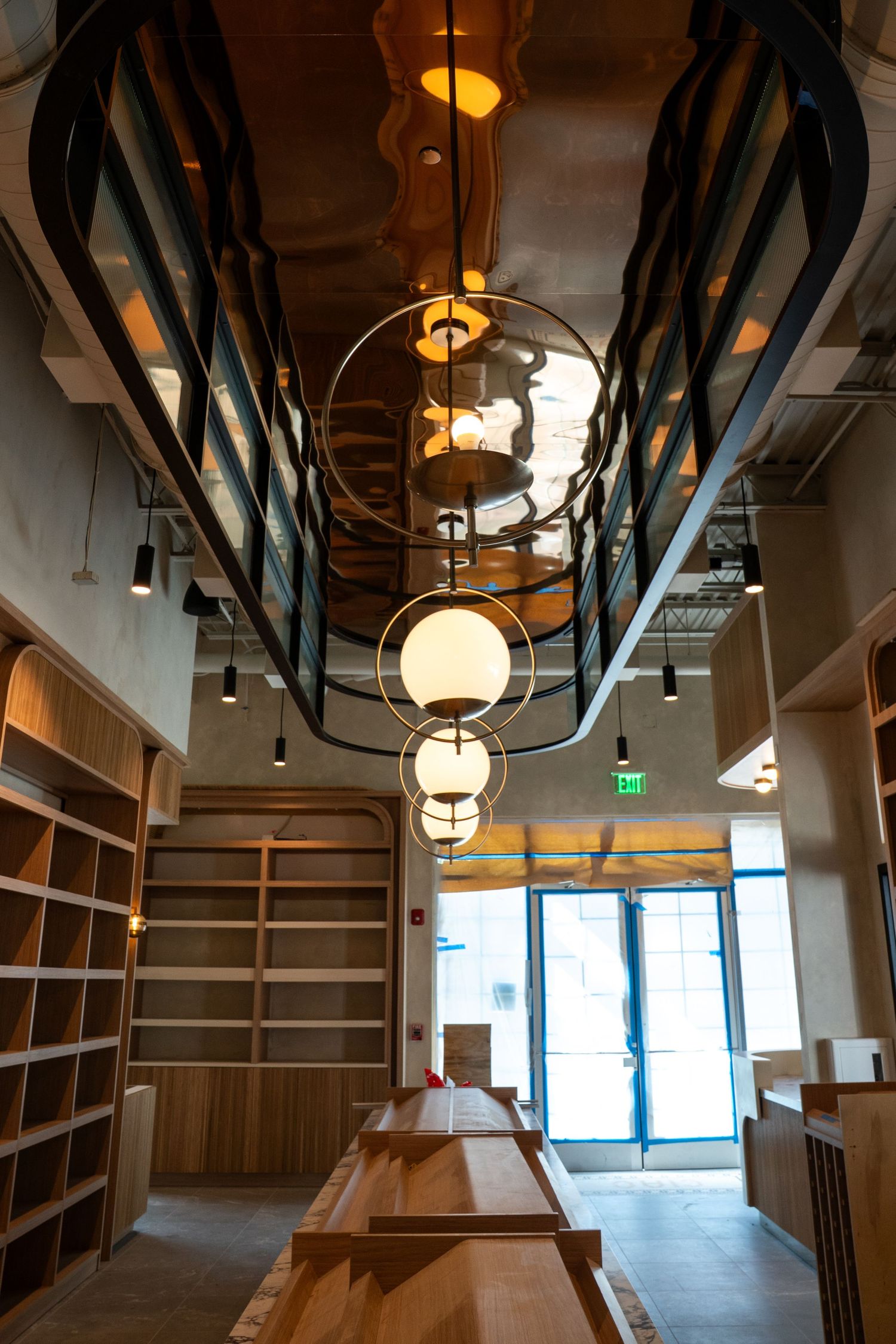 Modern office interior with wooden shelving, exposed ceiling beams, and pendant lighting creates an industrial yet warm atmosphere.