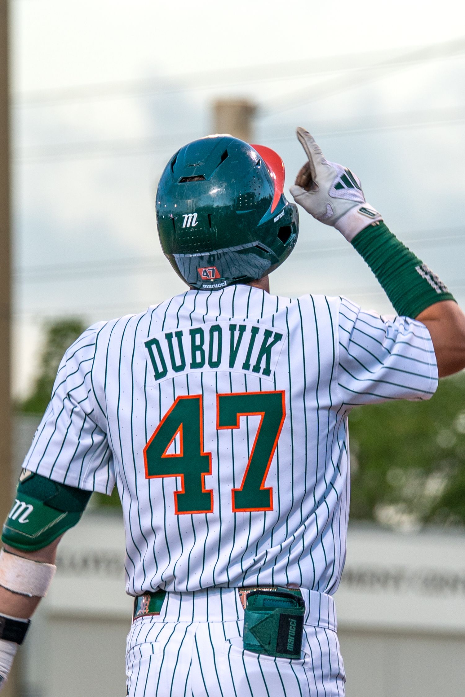 Baseball player Dubovik #47 in white pinstripe uniform points upward after a hit.