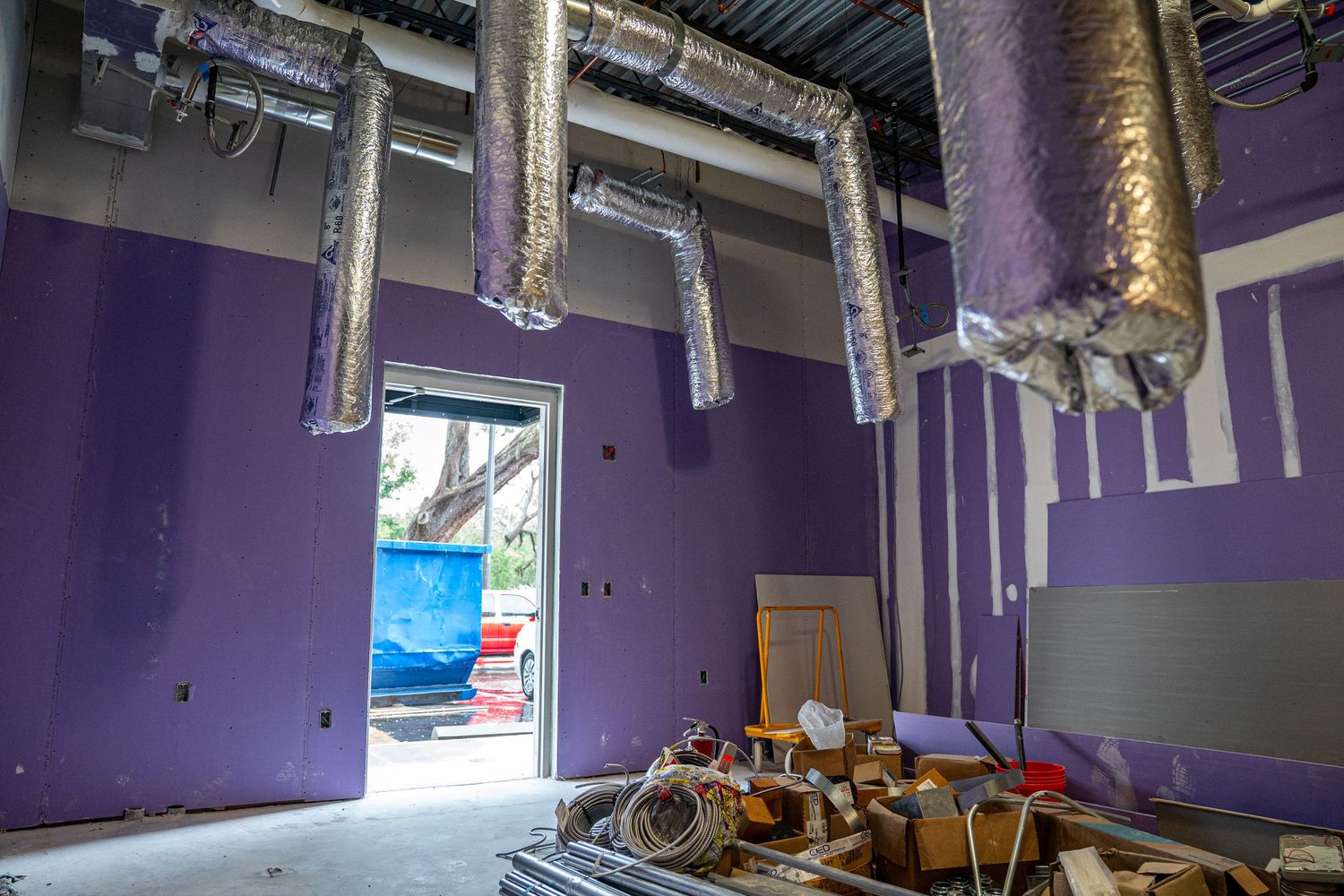 Purple-walled commercial space with exposed industrial ceiling and track lighting.