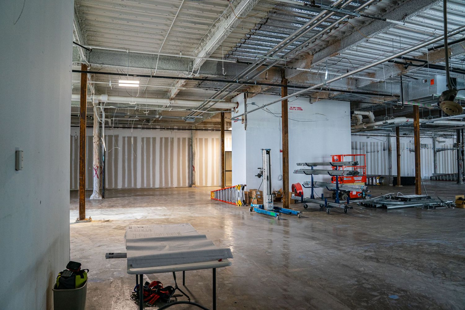 Wide angle view of vacant commercial warehouse interior with support columns and utility installations.