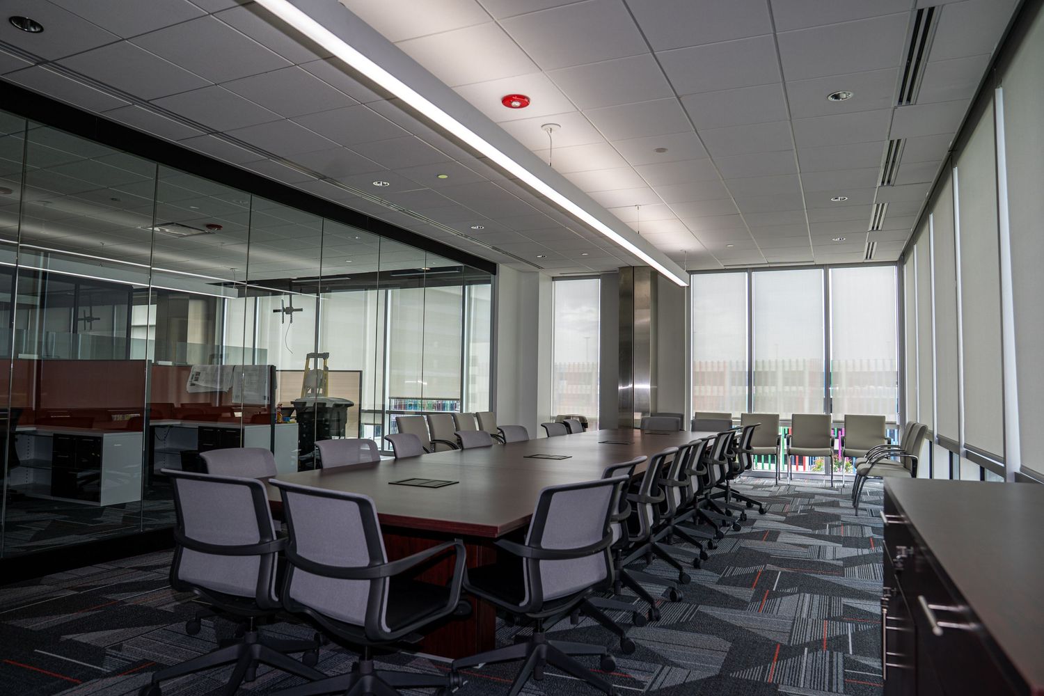 Spacious meeting room with large windows, modern furniture, and chevron-patterned carpeting.