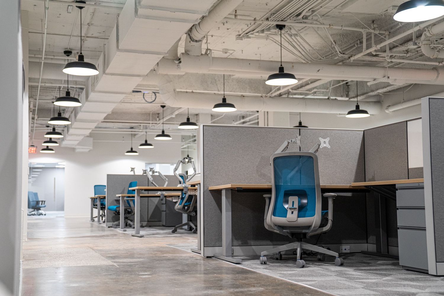 Industrial ceiling with exposed ductwork and pendant lights in white commercial space.