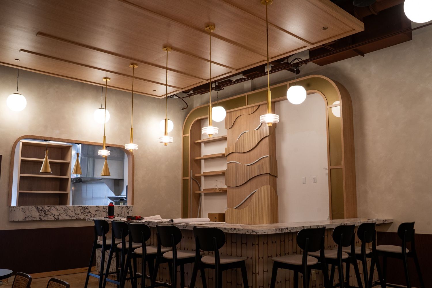 Modern restaurant interior with pendant lights, exposed concrete walls, and minimalist wooden furniture.