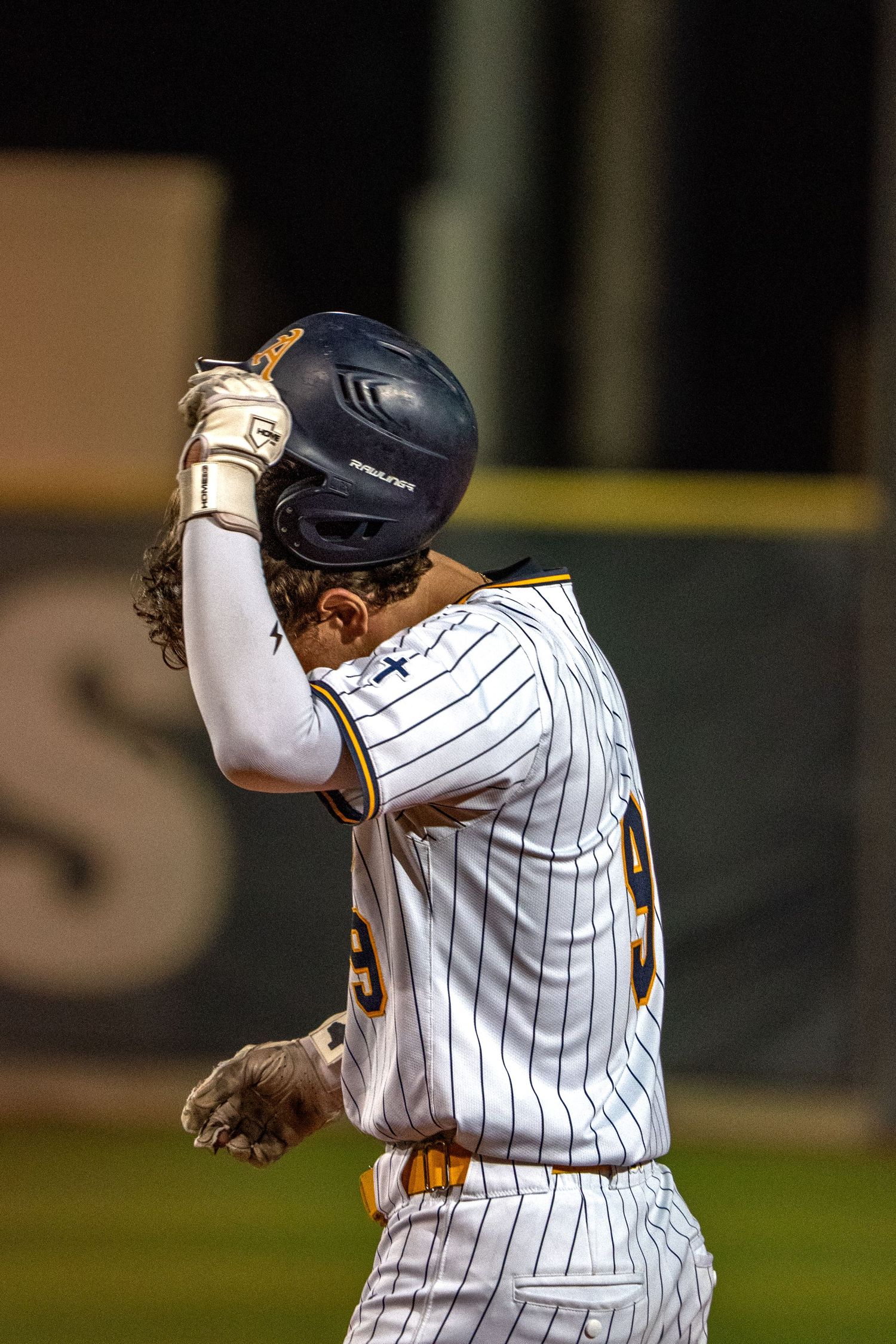Baseball player in pinstriped uniform celebrating during a night game.
