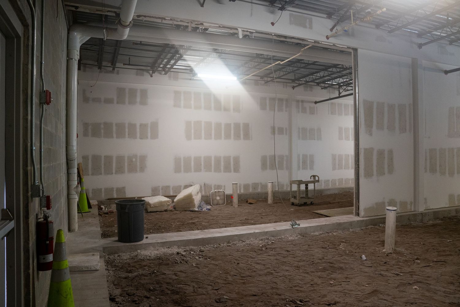 Long empty warehouse interior with concrete floors and industrial lighting system.