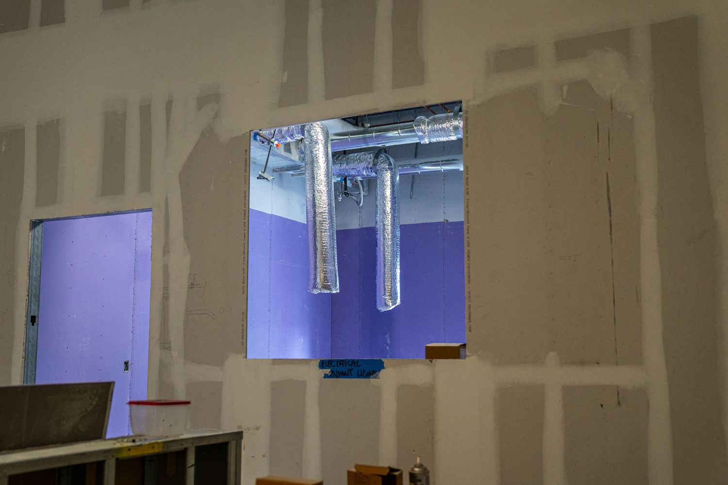 Unfinished commercial space with white drywall and exposed ceiling infrastructure.