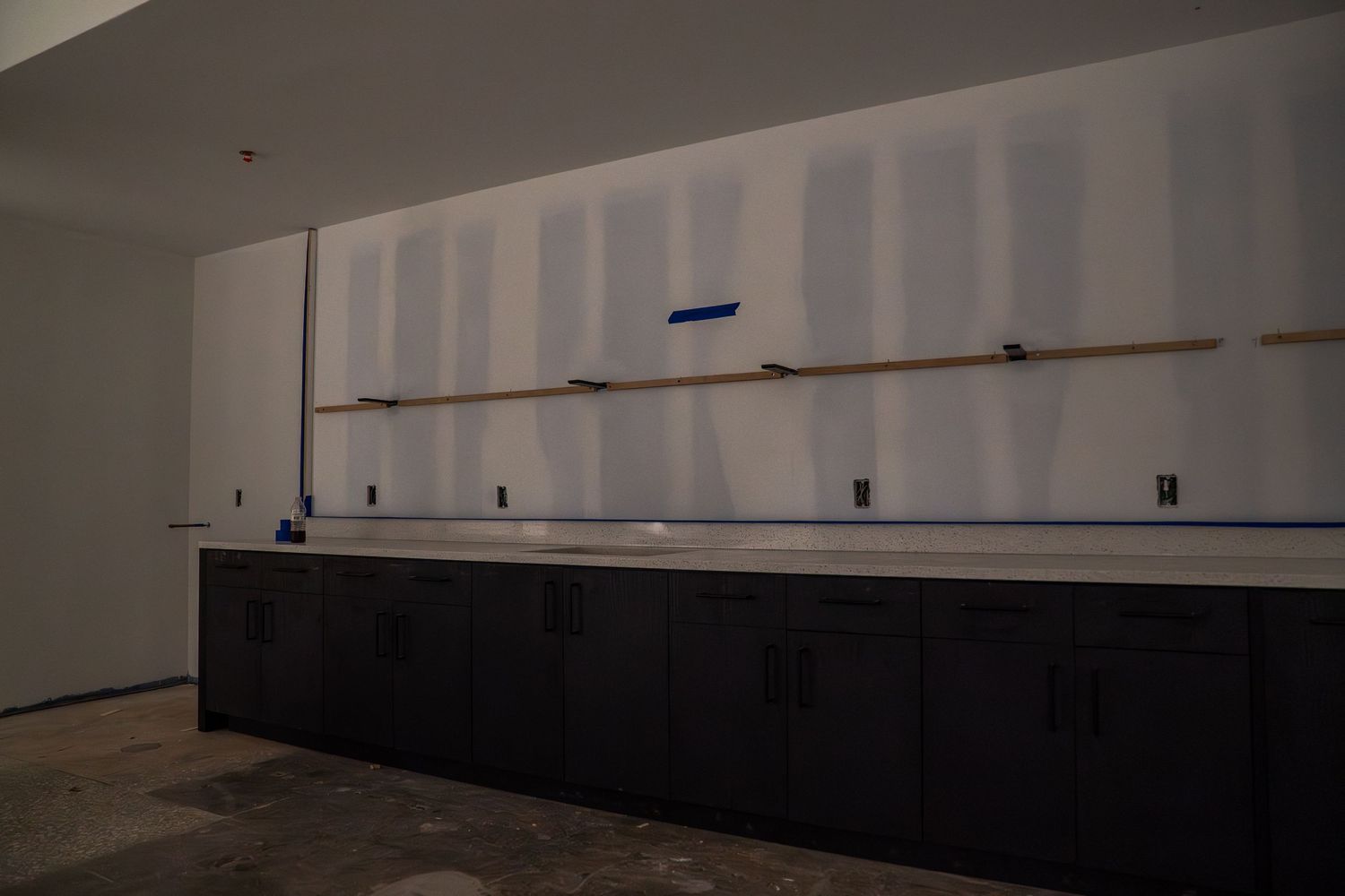 Commercial space showing newly installed white walls with dark base trim during construction.