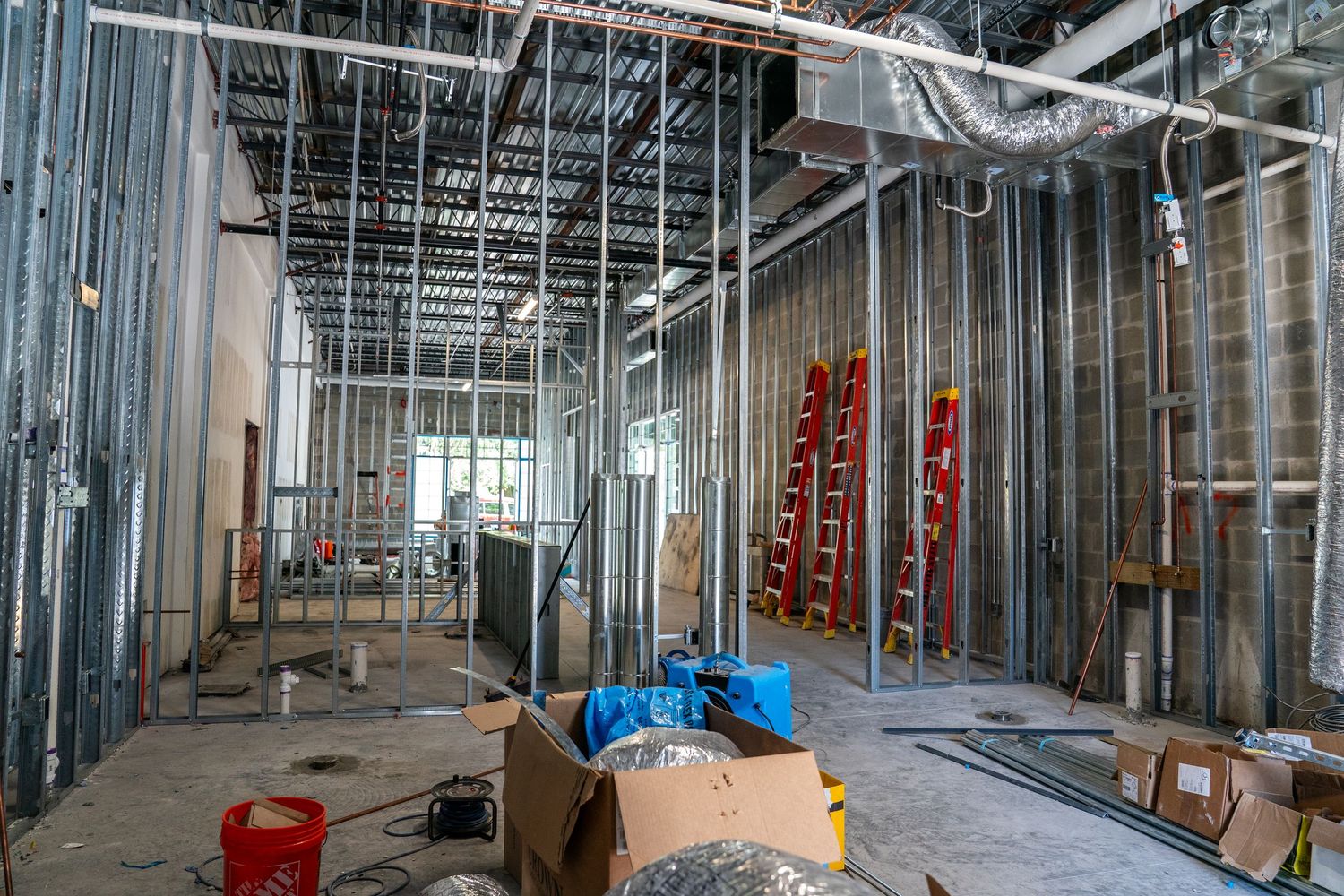 Construction materials and equipment scattered throughout unfinished commercial space.