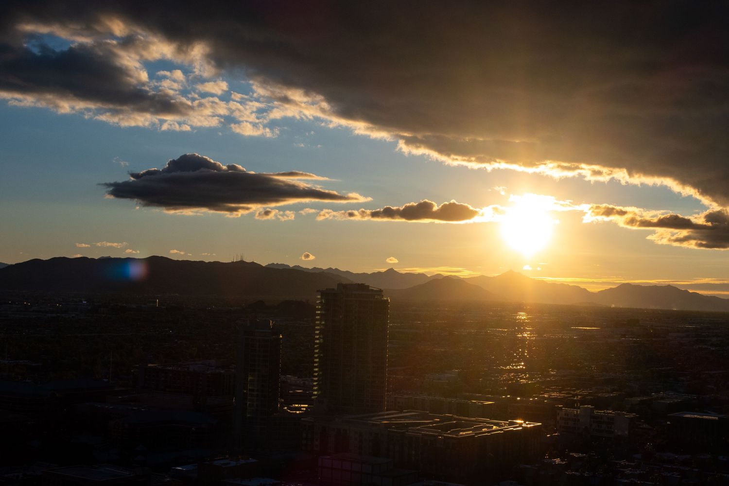 Dramatic sunset silhouette over city skyline with dark clouds.