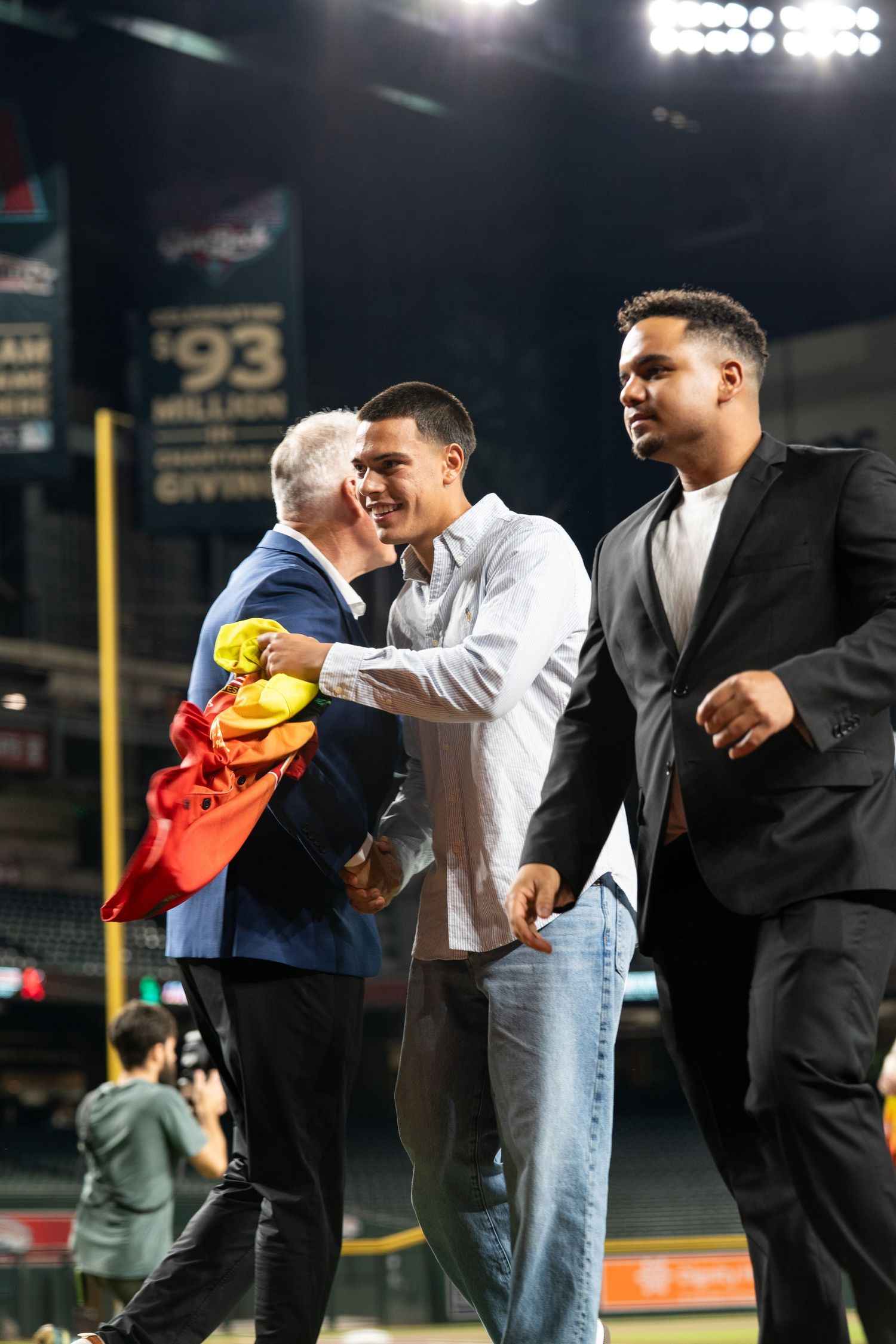 Group gathering on baseball field at night with sports memorabilia.
