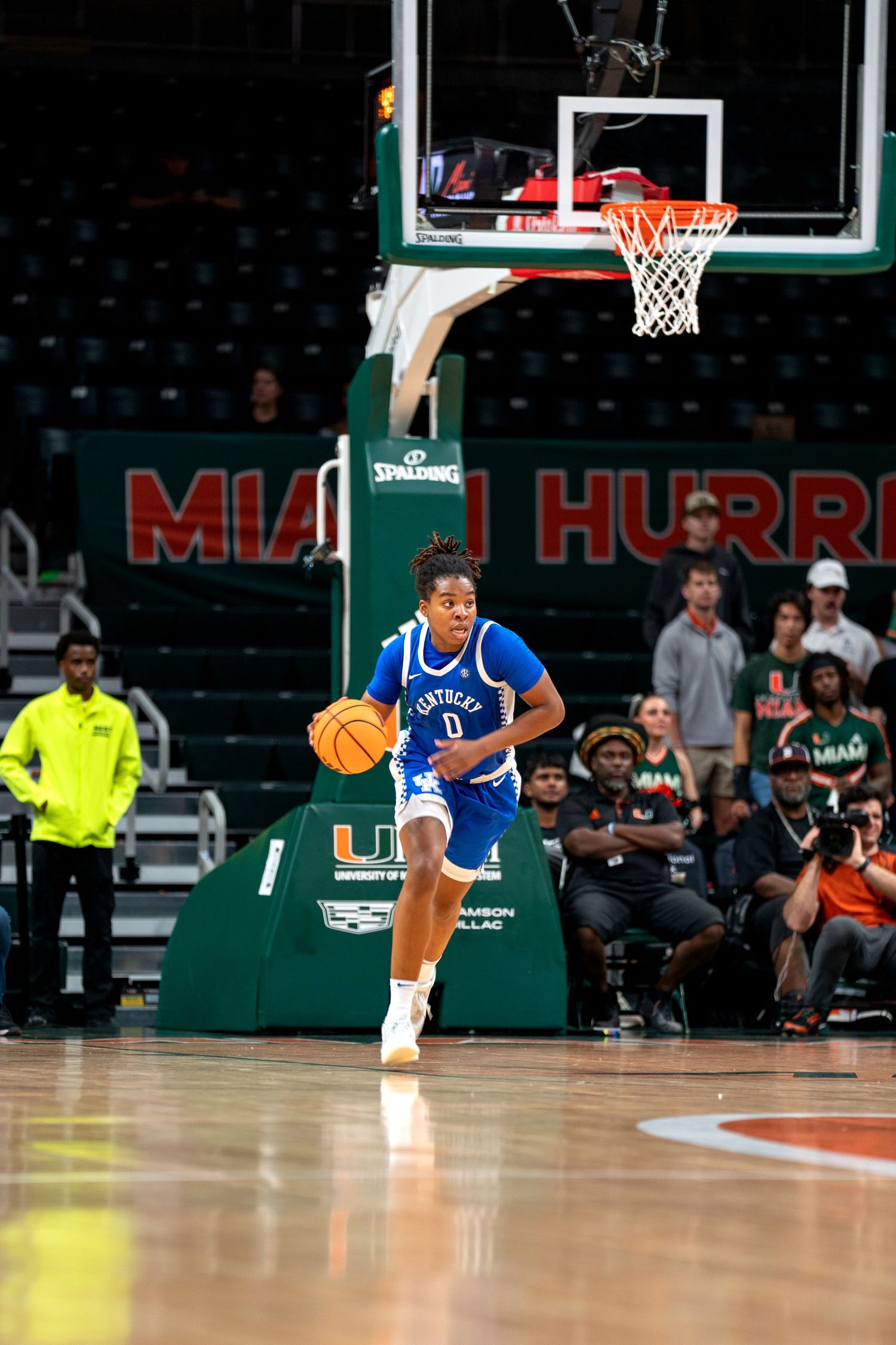 Basketball player in Kentucky uniform dribbles down court during match.