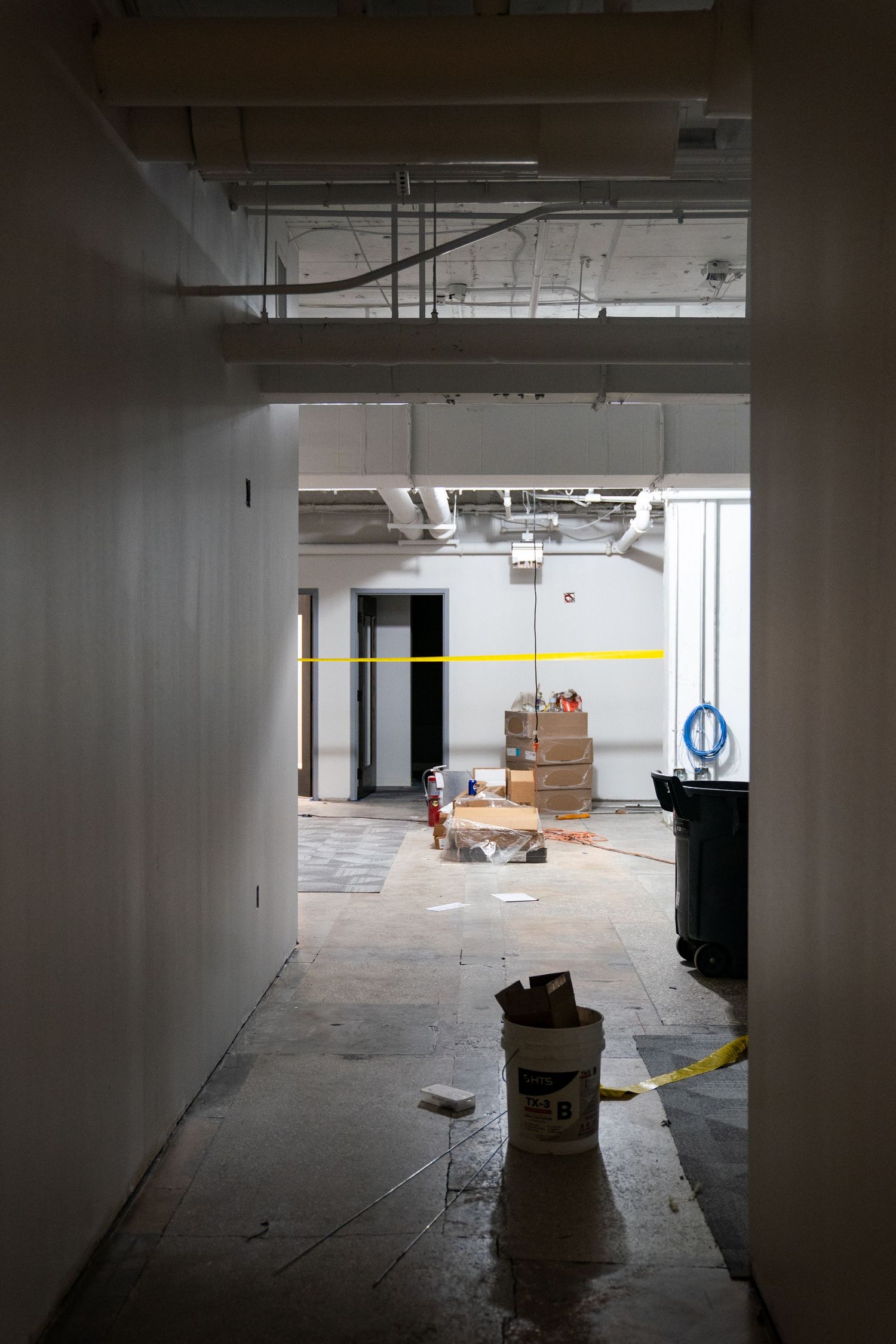 Dark industrial space under renovation with exposed ceiling and construction materials.