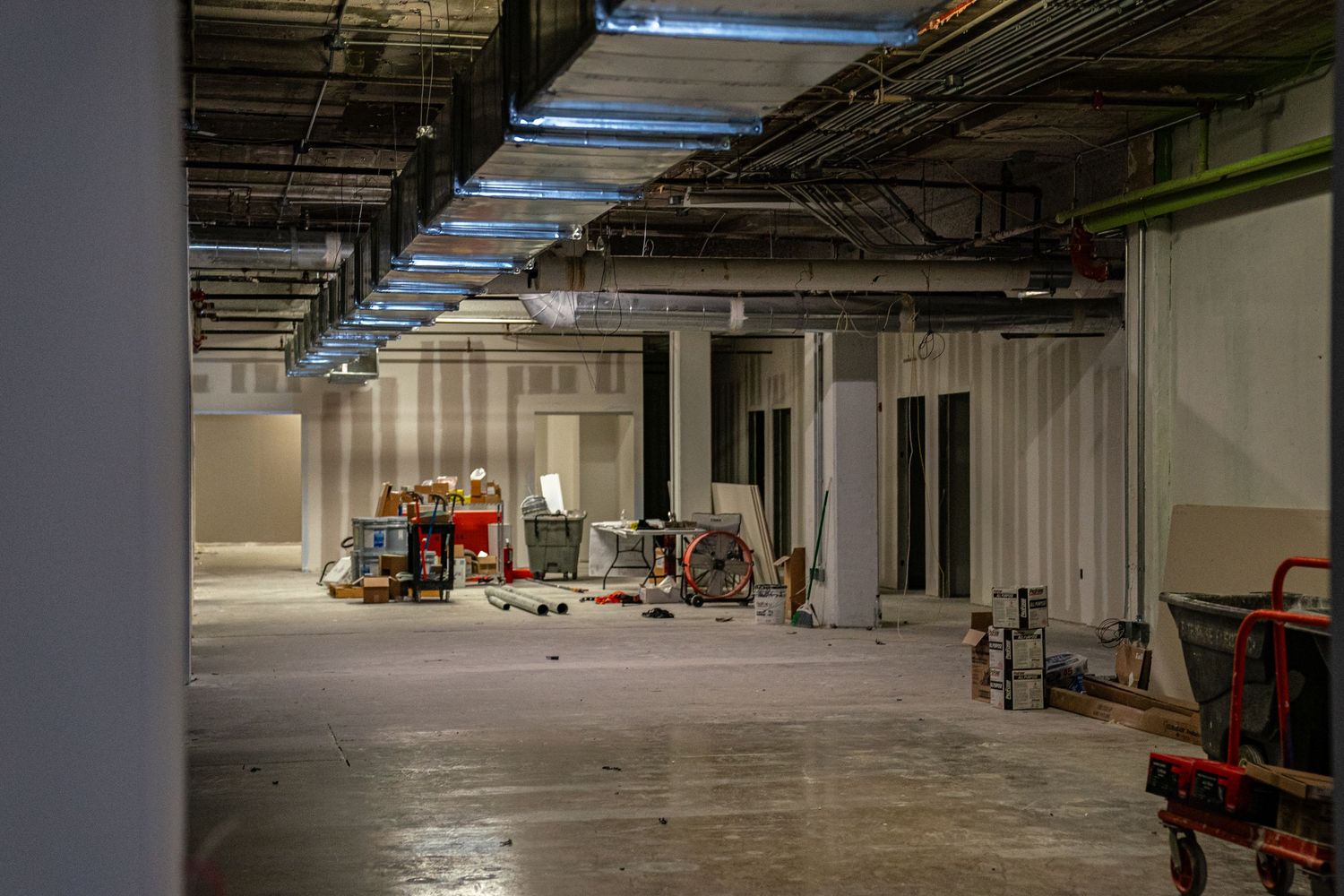 Large empty warehouse space with exposed ceiling and industrial lighting fixtures.