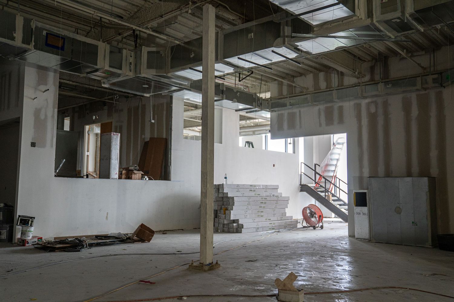 Empty industrial space with exposed mechanical systems and natural lighting.