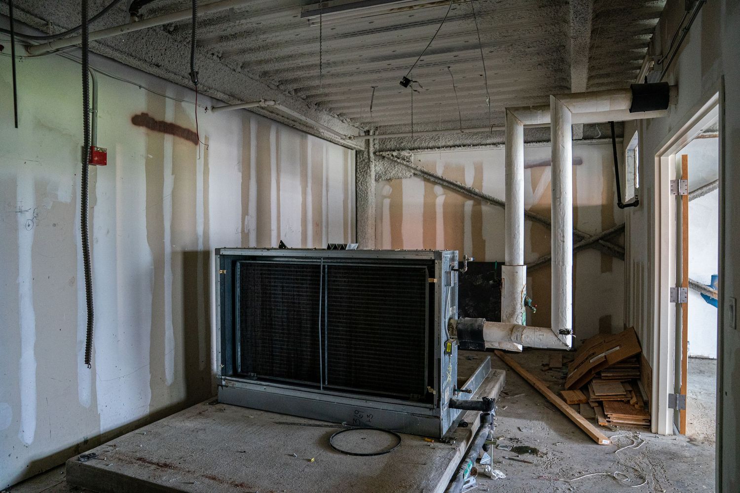 Panoramic view of an unfinished commercial space with white walls and exposed mechanical systems.