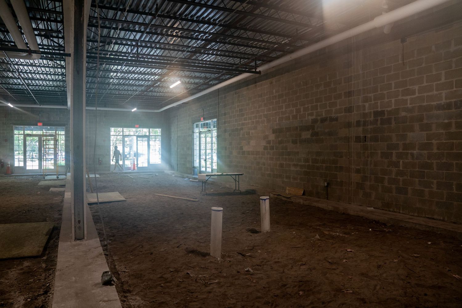 Industrial space with brick walls and exposed ceiling infrastructure under construction.