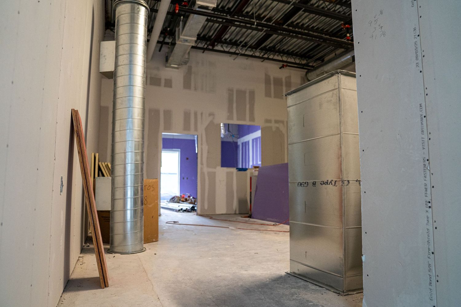 Industrial style interior with exposed ductwork and unfinished walls during renovation.