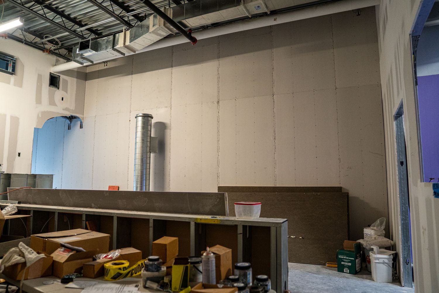 Empty industrial space under construction with exposed ceiling and white walls.