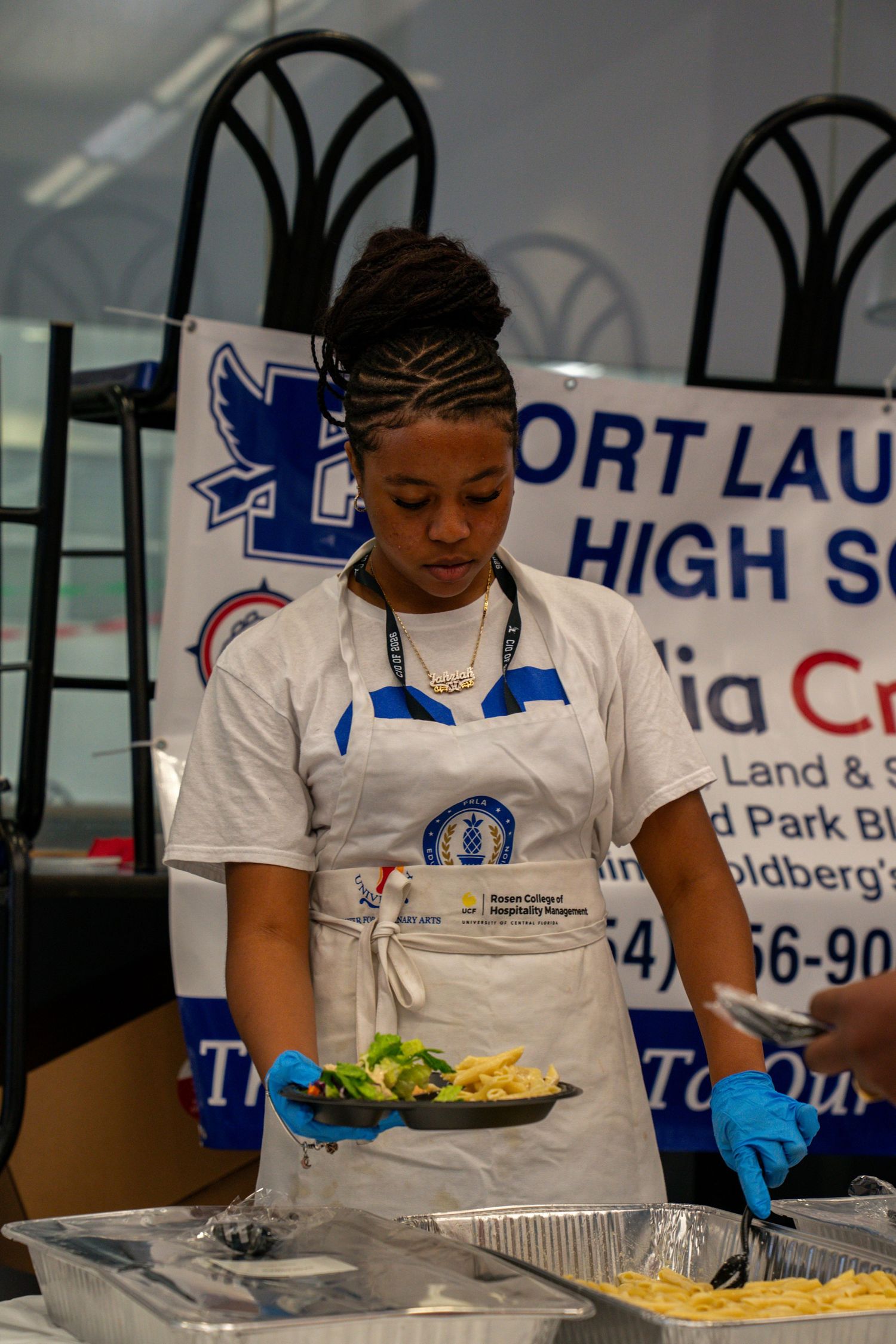 Students in white uniforms prepare food at Fort Lauderdale High School.