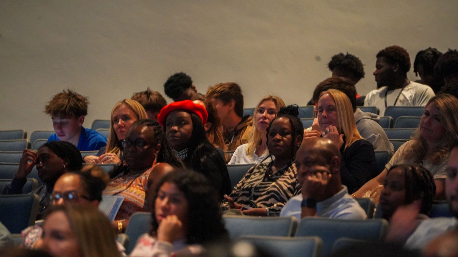 Engaged audience members watch attentively in theater seating.