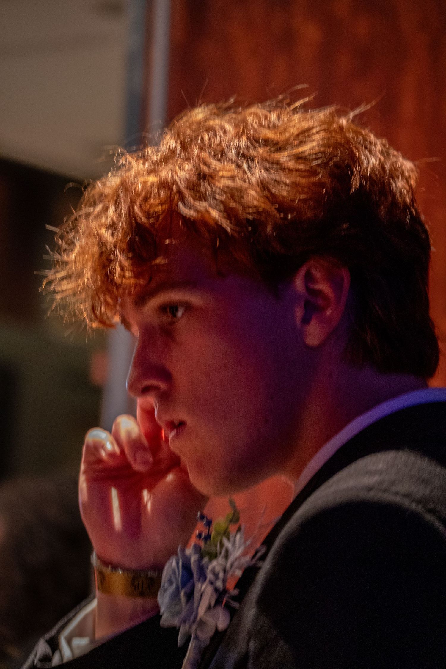 Profile view of a person in formal attire illuminated by warm lighting.