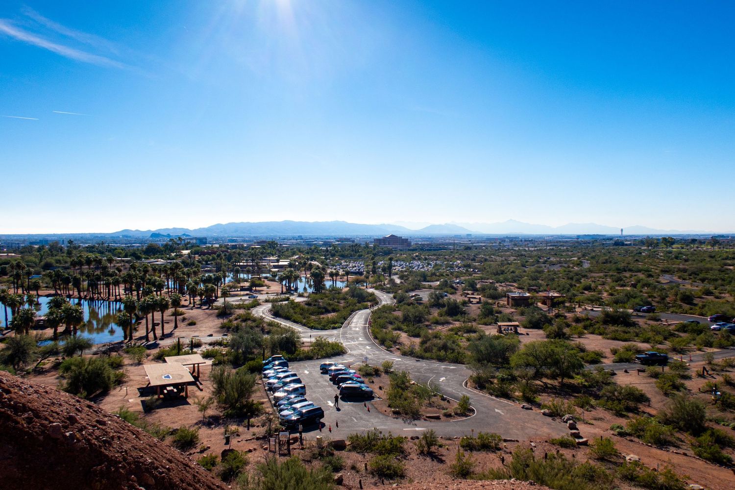 Aerial view of desert city with parking lots and buildings surrounded by mountain landscape.