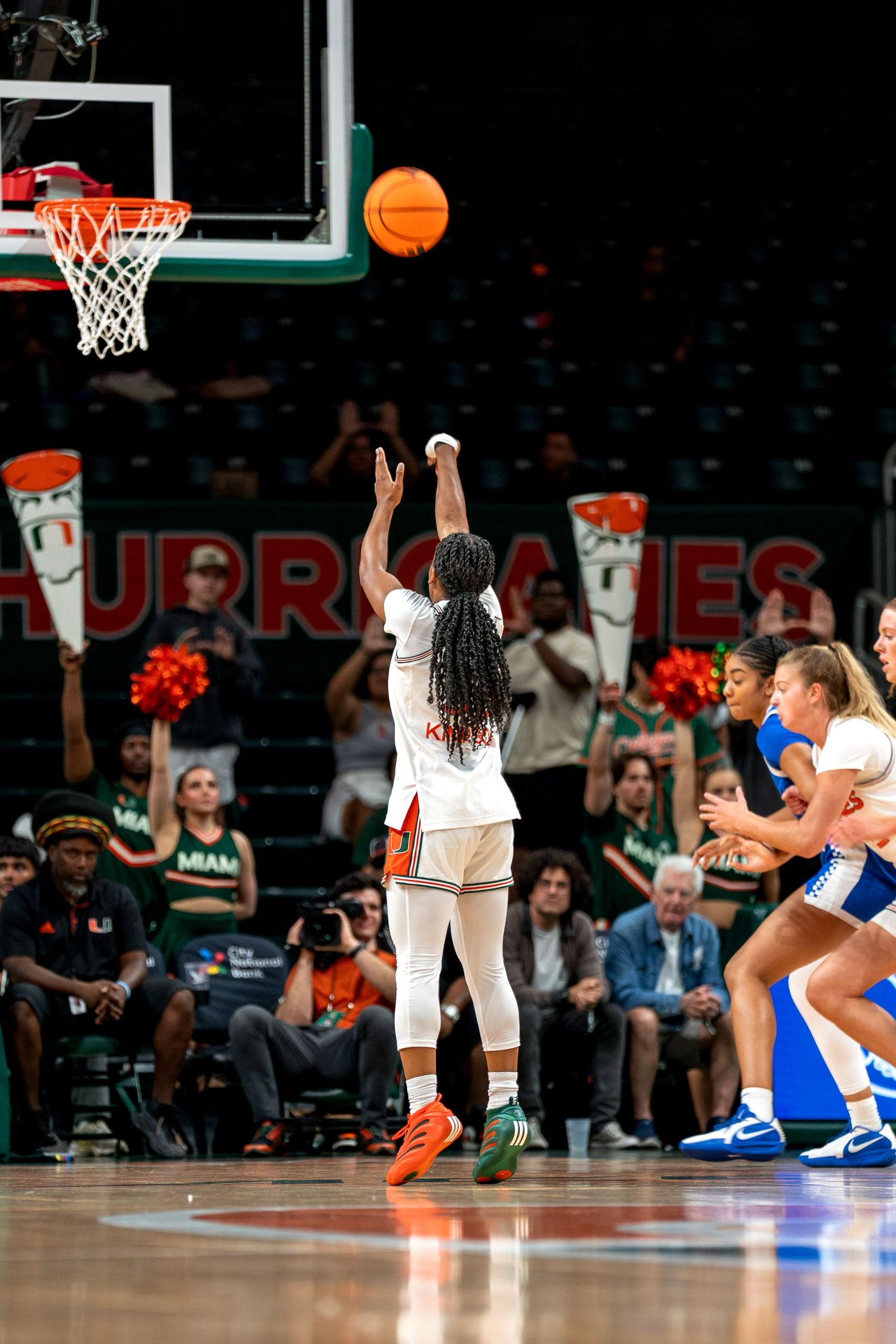 Basketball in mid-air as players compete during a Miami Hurricanes game.